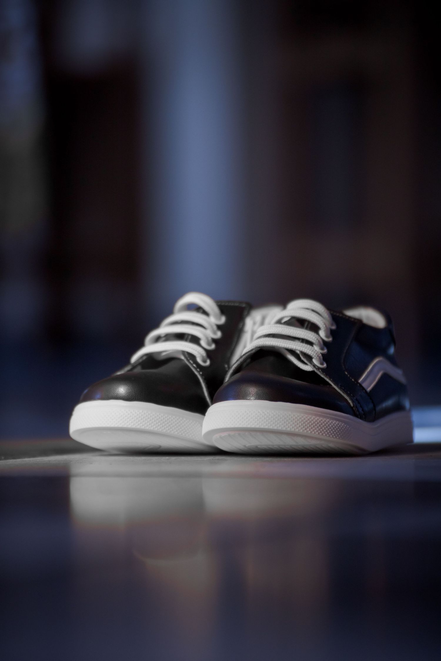 Classic navy and white sneakers arranged on dark surface.