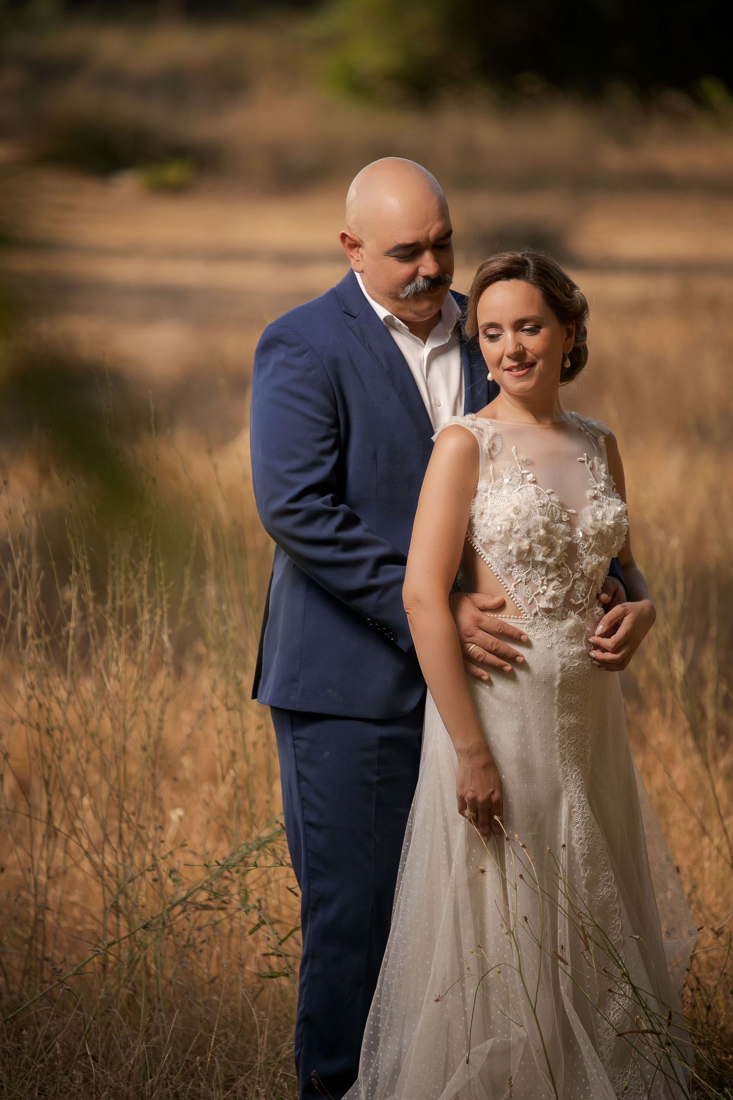Romantic couple portrait in a golden field wearing formal attire.