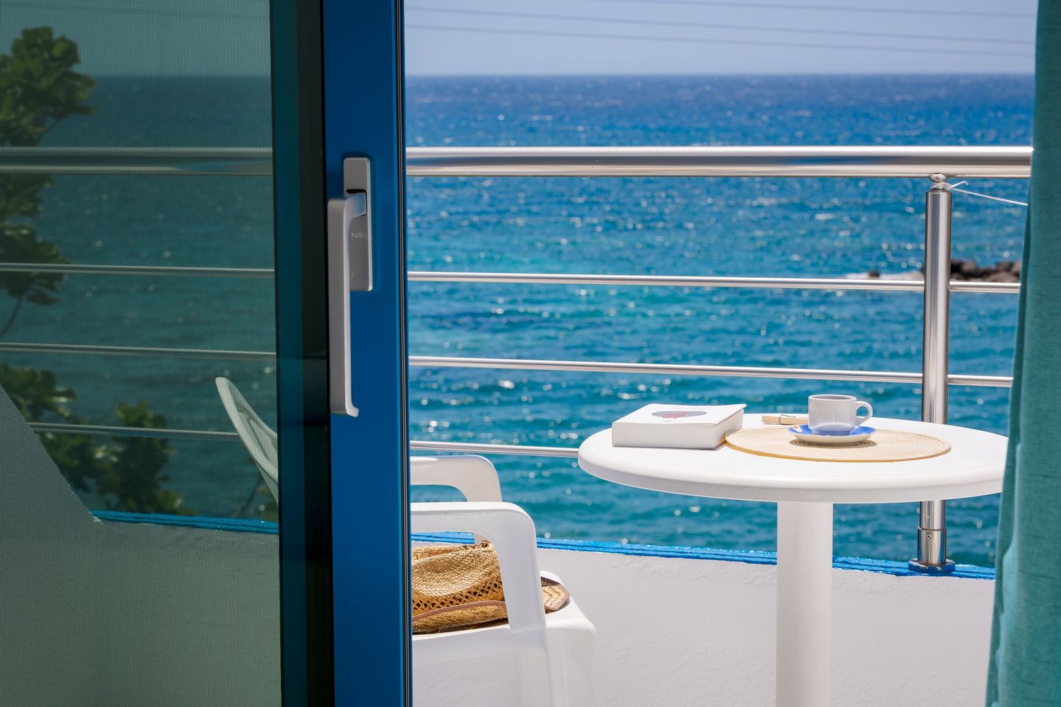 White terrace overlooking crystal clear Mediterranean waters with dining setup.