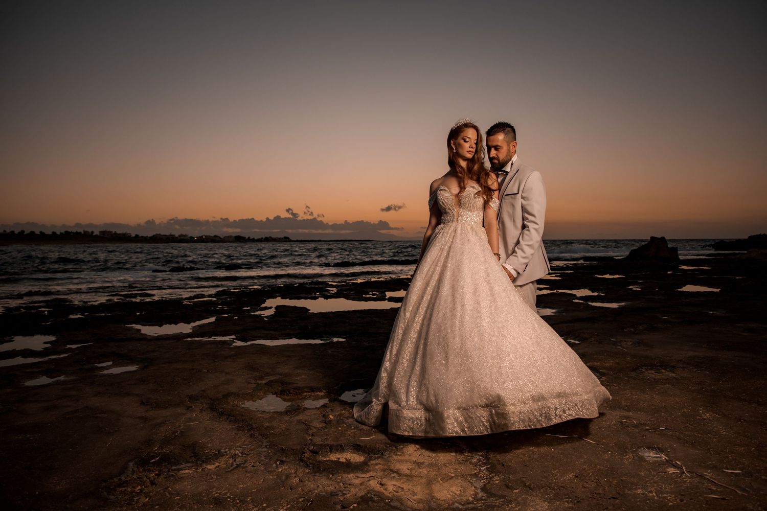 Seaside wedding photography at sunset with rocky coastline and ocean views.