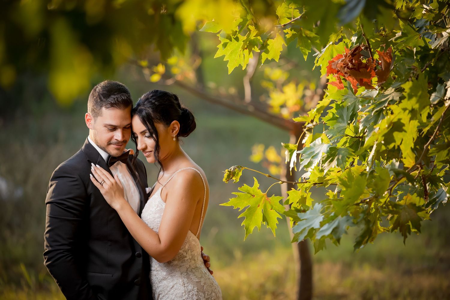 Wedding couple embraces under golden maple leaves during autumn photo session.
