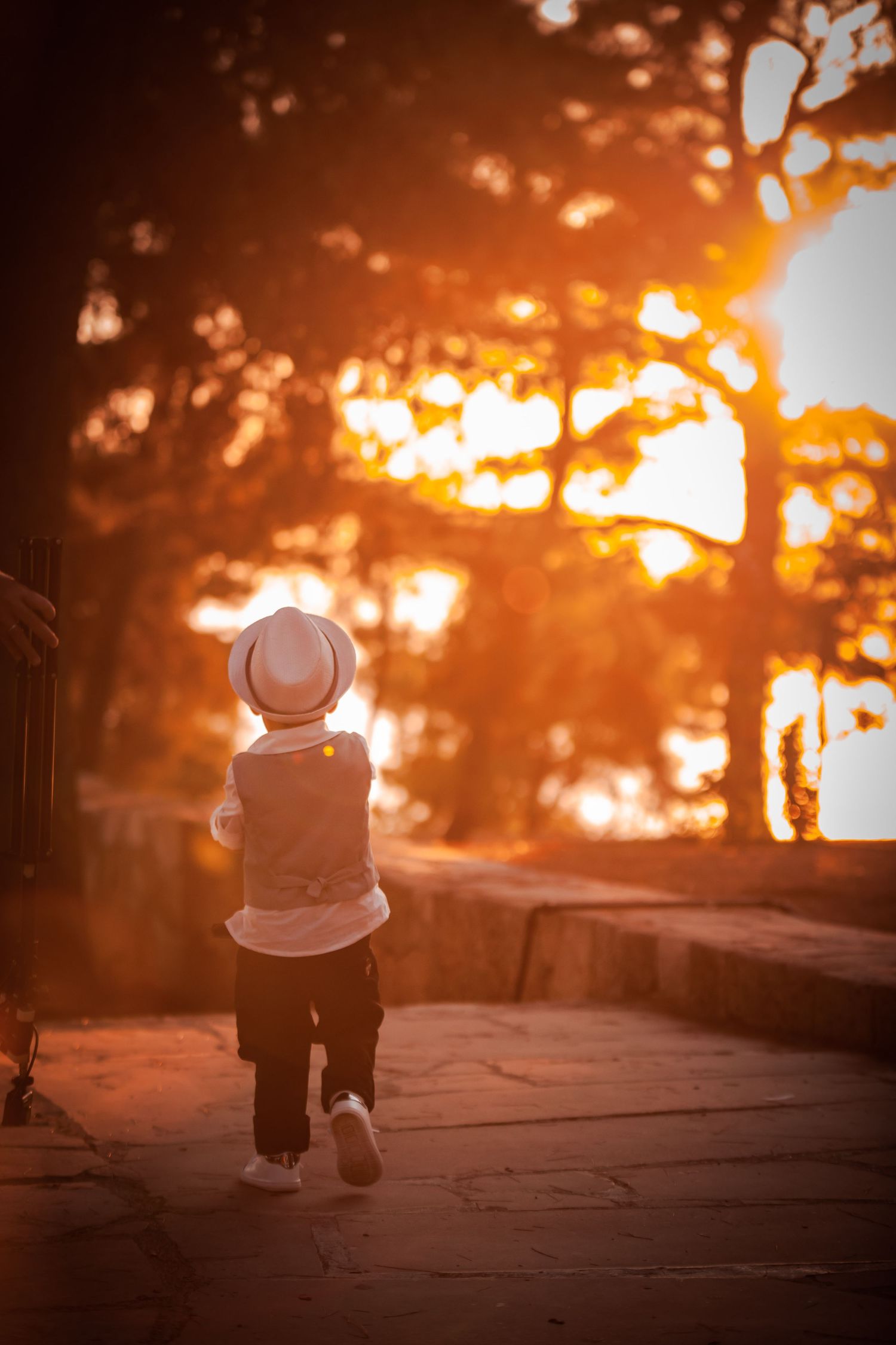 Two people walking together at sunset with glowing orange light behind them.
