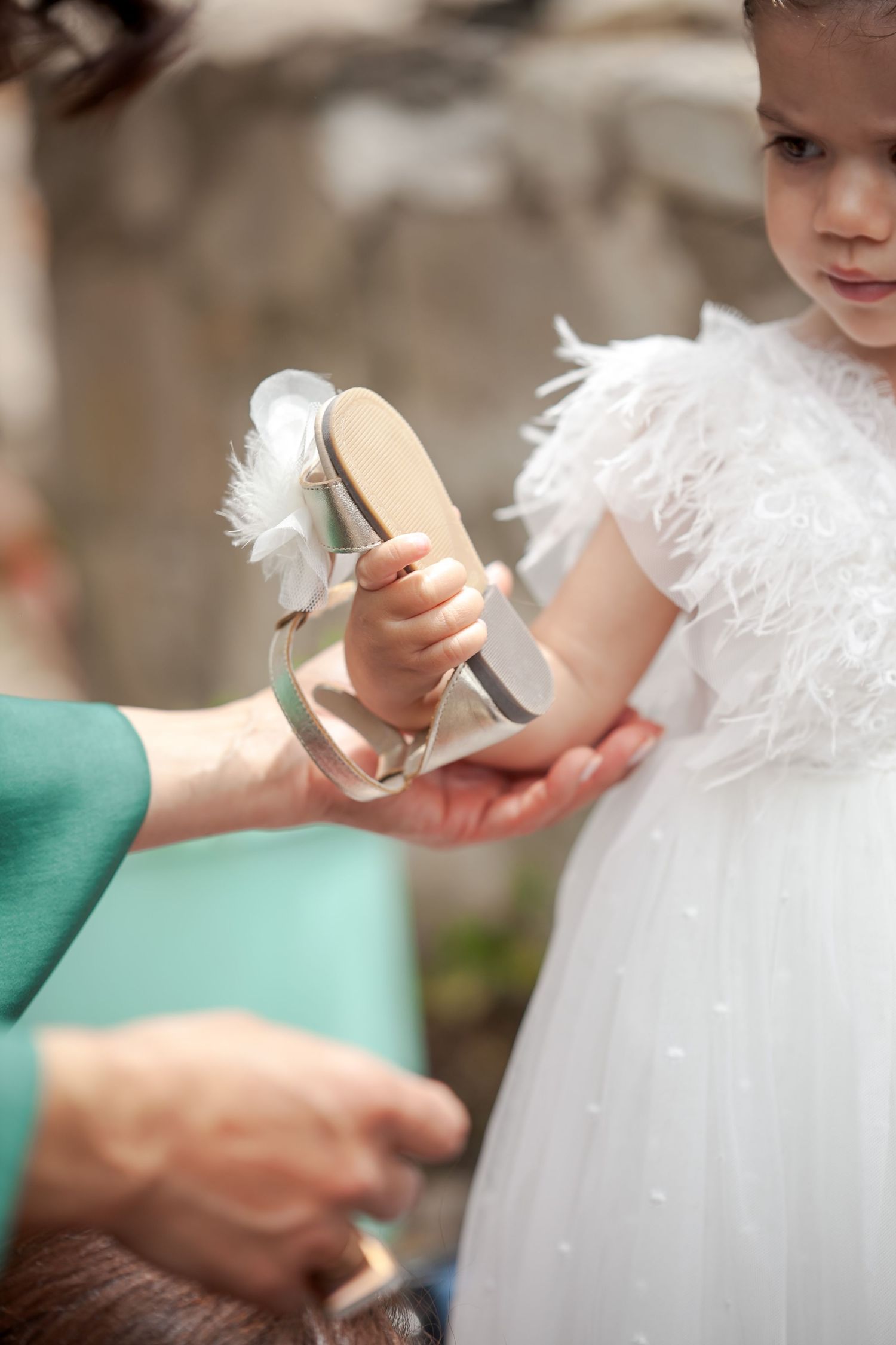 Small hands touching delicate white feathered details on formal attire.