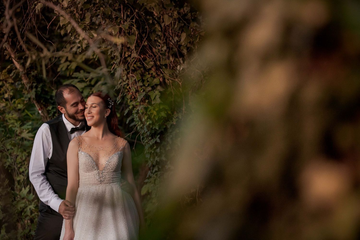 Intimate moment captured through branches in natural outdoor setting.