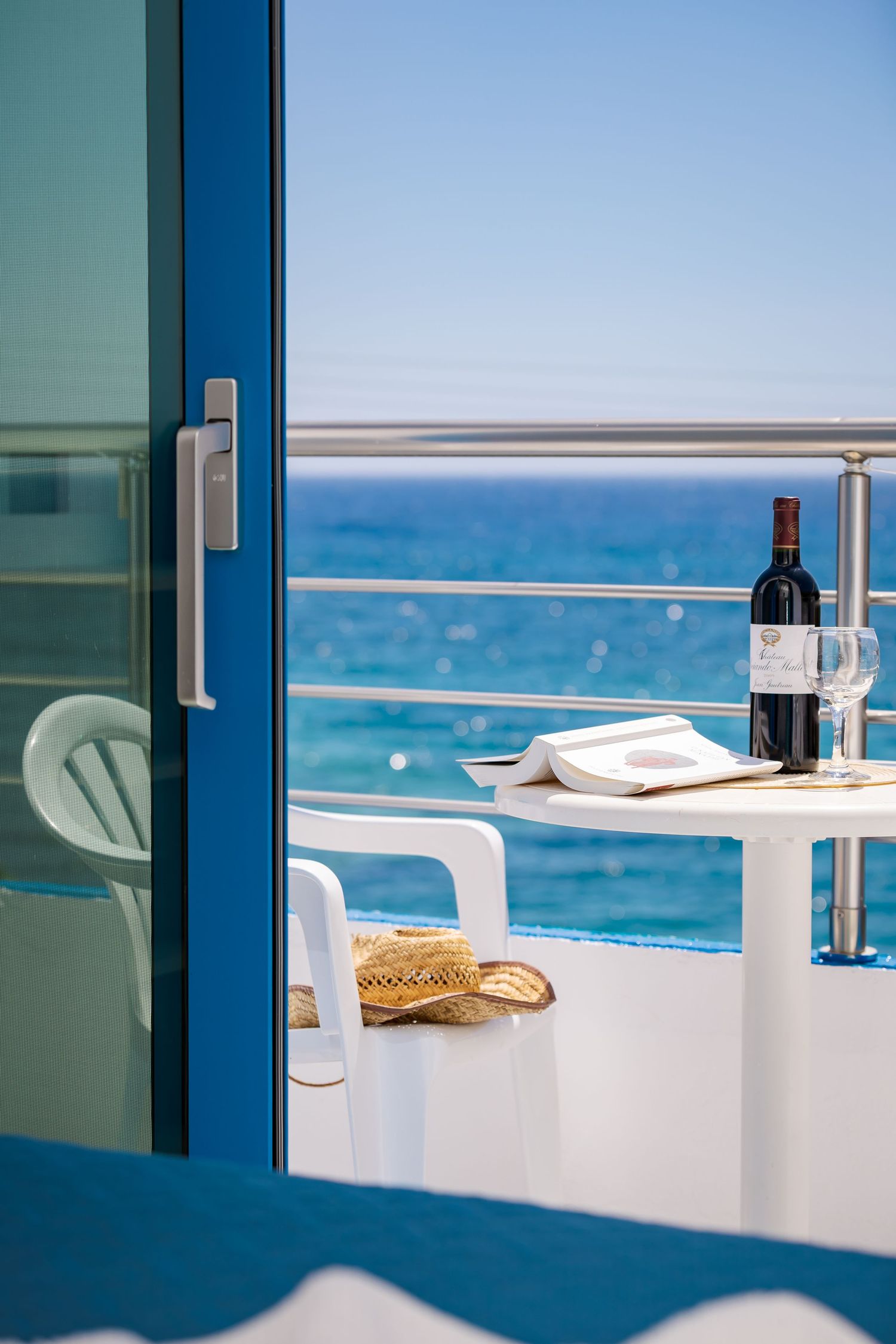 Oceanfront balcony table set with wine and stunning blue water views.