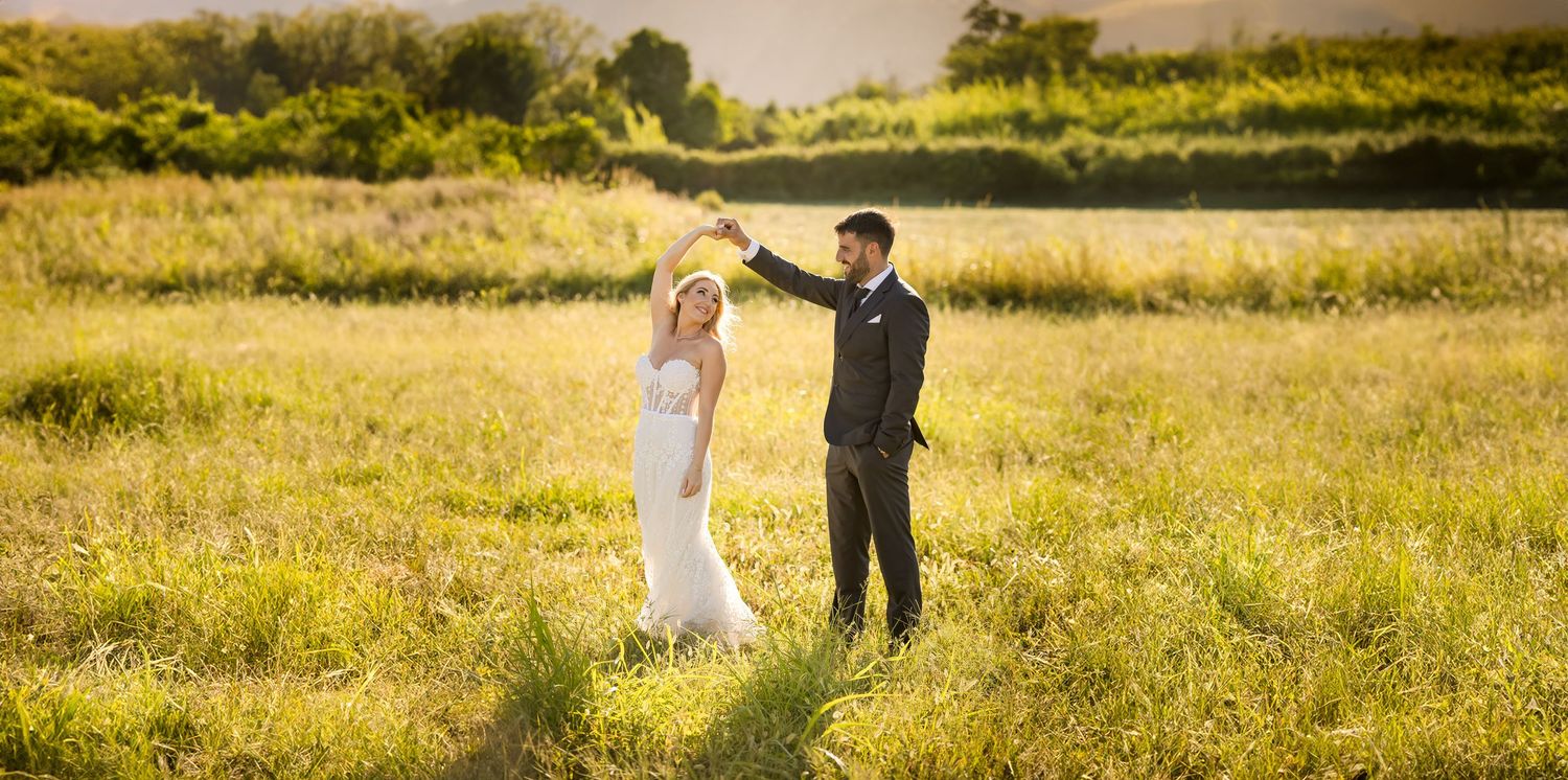 Wedding couple walking through sun-drenched meadow during golden hour.