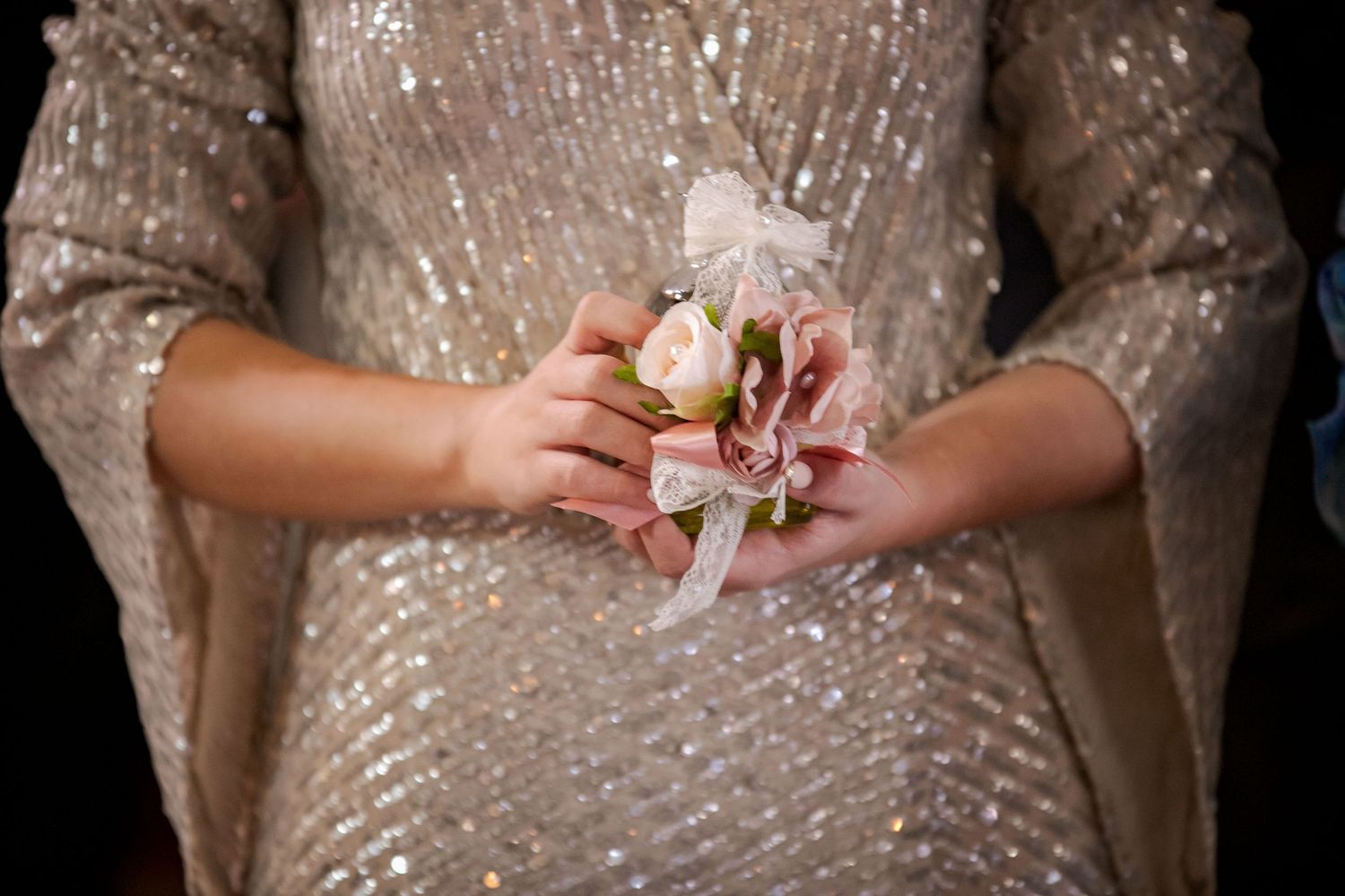 Close-up of hands against champagne sequined dress material.