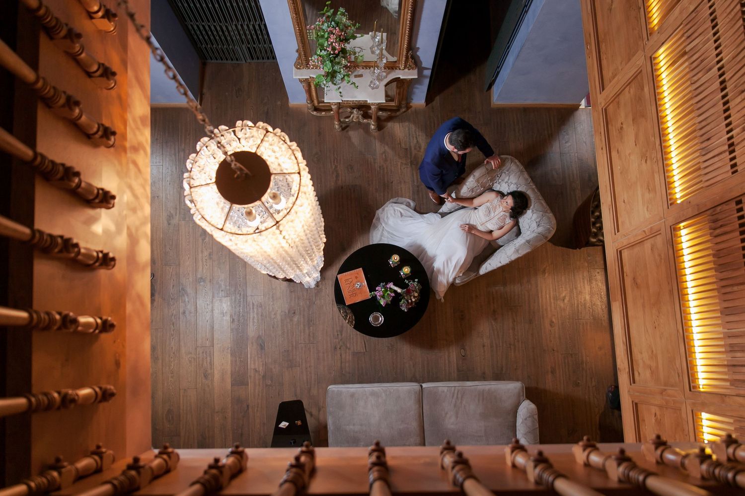 Overhead view of wedding celebration in elegant wooden-floored venue with warm lighting.