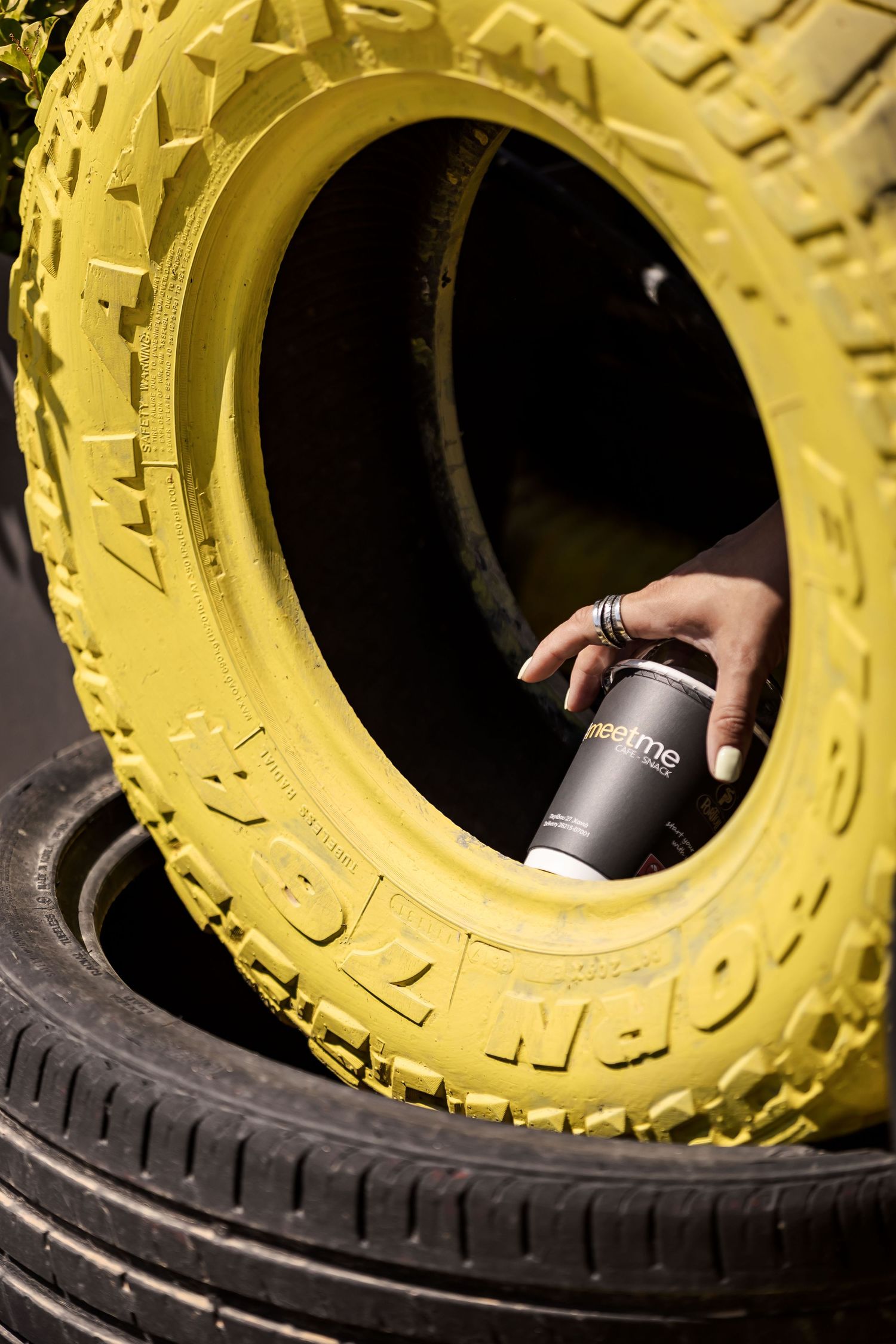 Hand positions can of beverage into center hole of yellow industrial tire to demonstrate unique container cooling method.