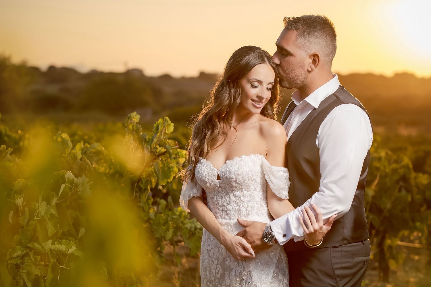 Golden hour wedding portraits in a vineyard with soft glowing sunlight.