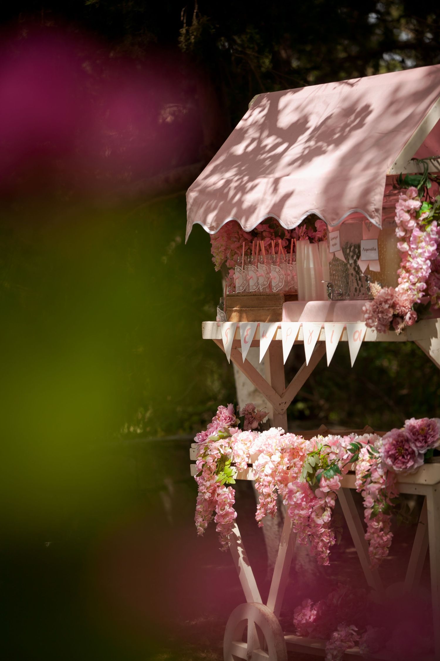 White wooden pergola decorated with pink floral arrangements and bunting.