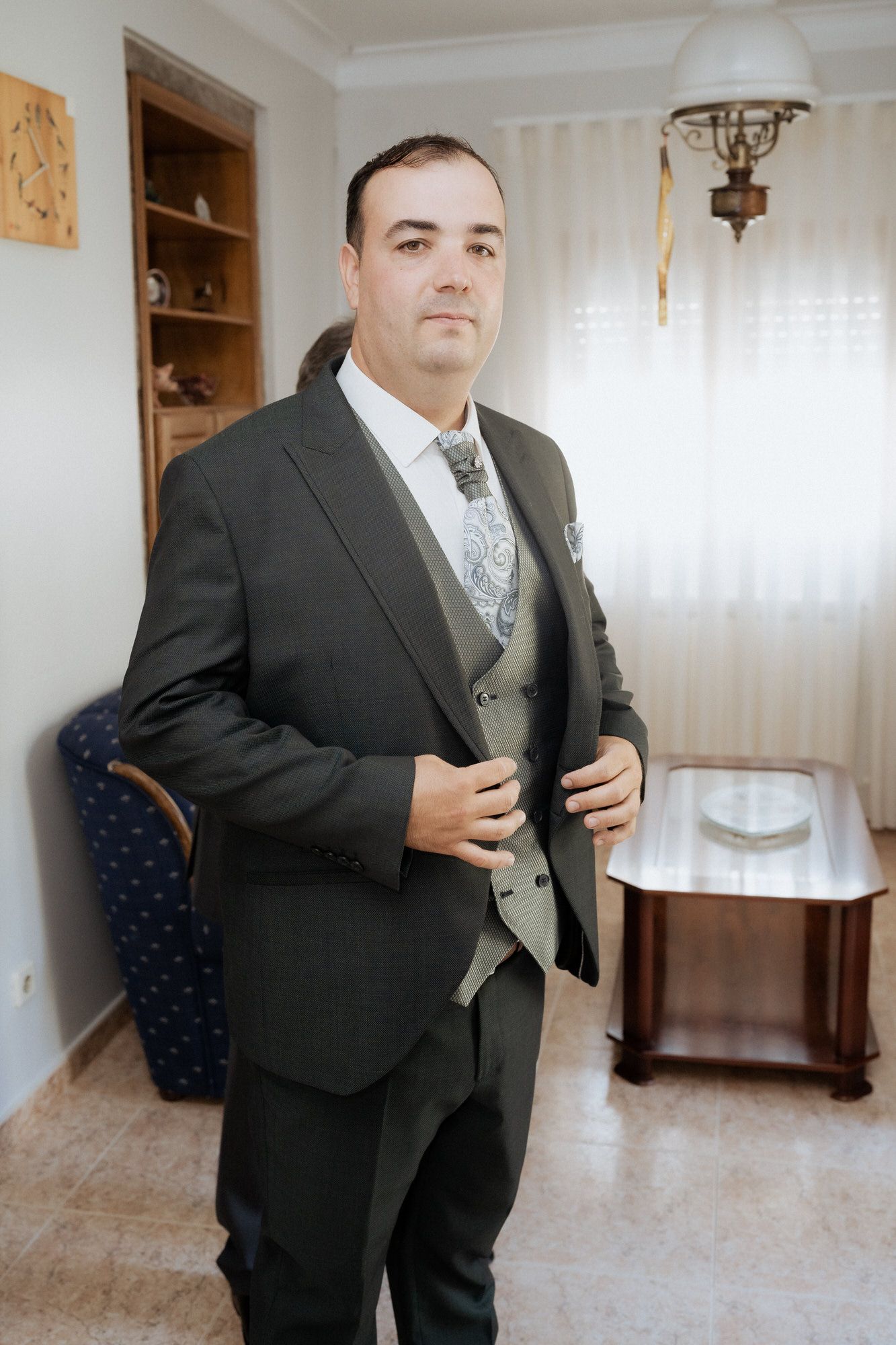 A series of photos showing groom preparation in formalwear with black suit and silver vest in a bright room.