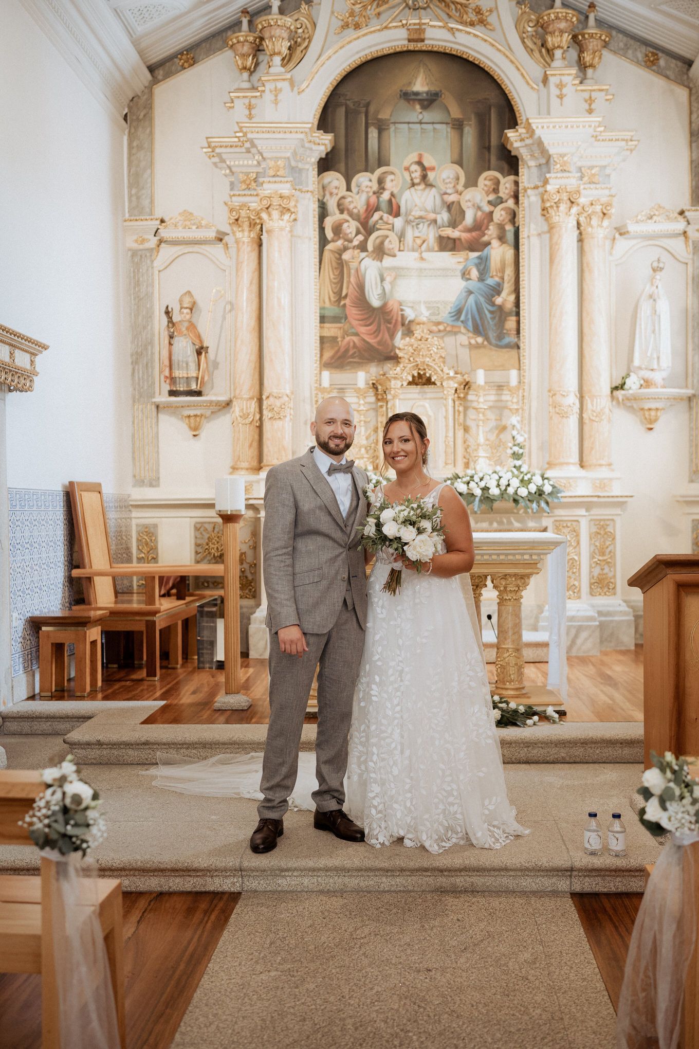Beautiful church wedding ceremony with ornate baroque altar and floral decorations in elegant white and gold interior.