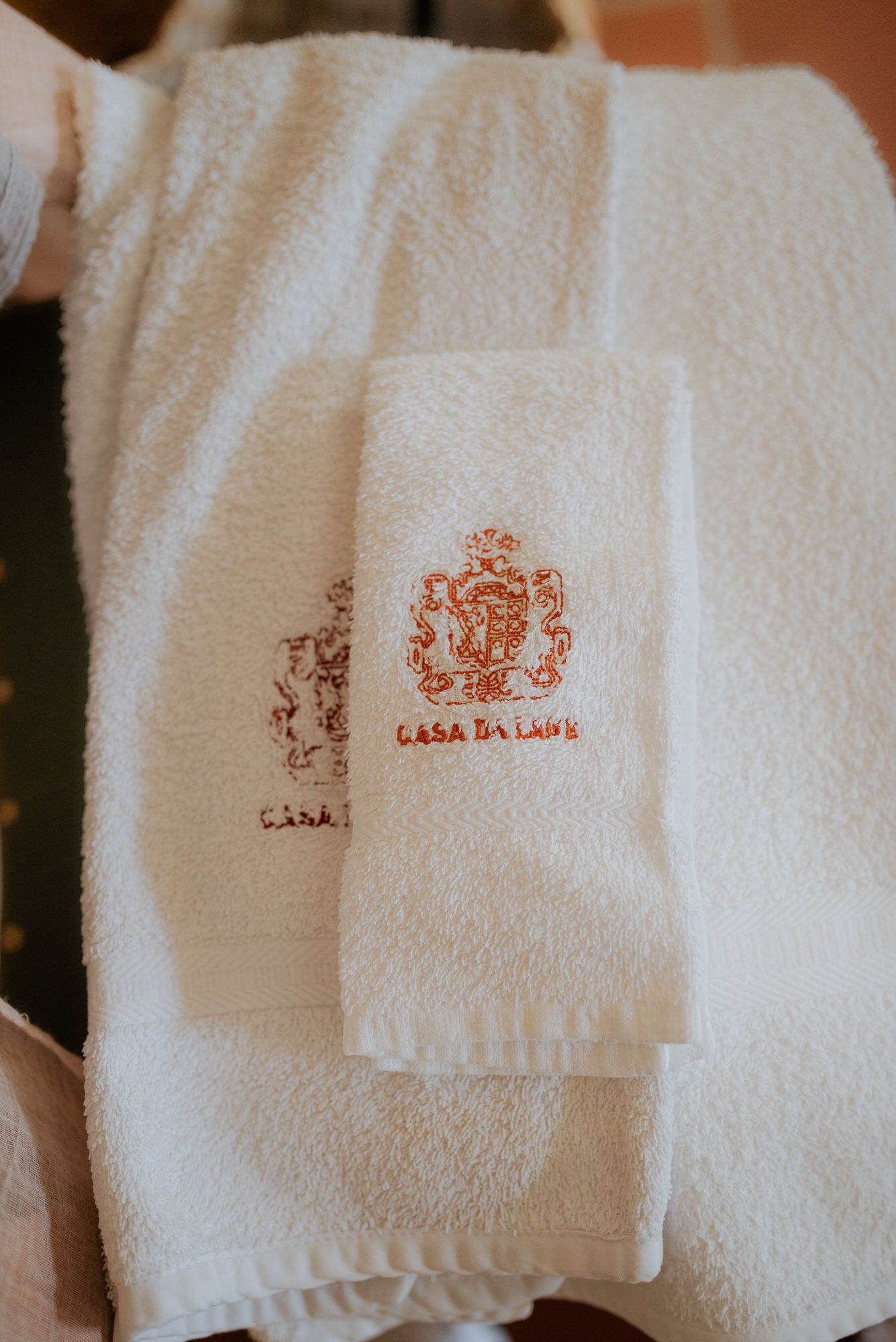 Clean white hotel towels with embroidered Casa Da Laura logo neatly folded and stacked.