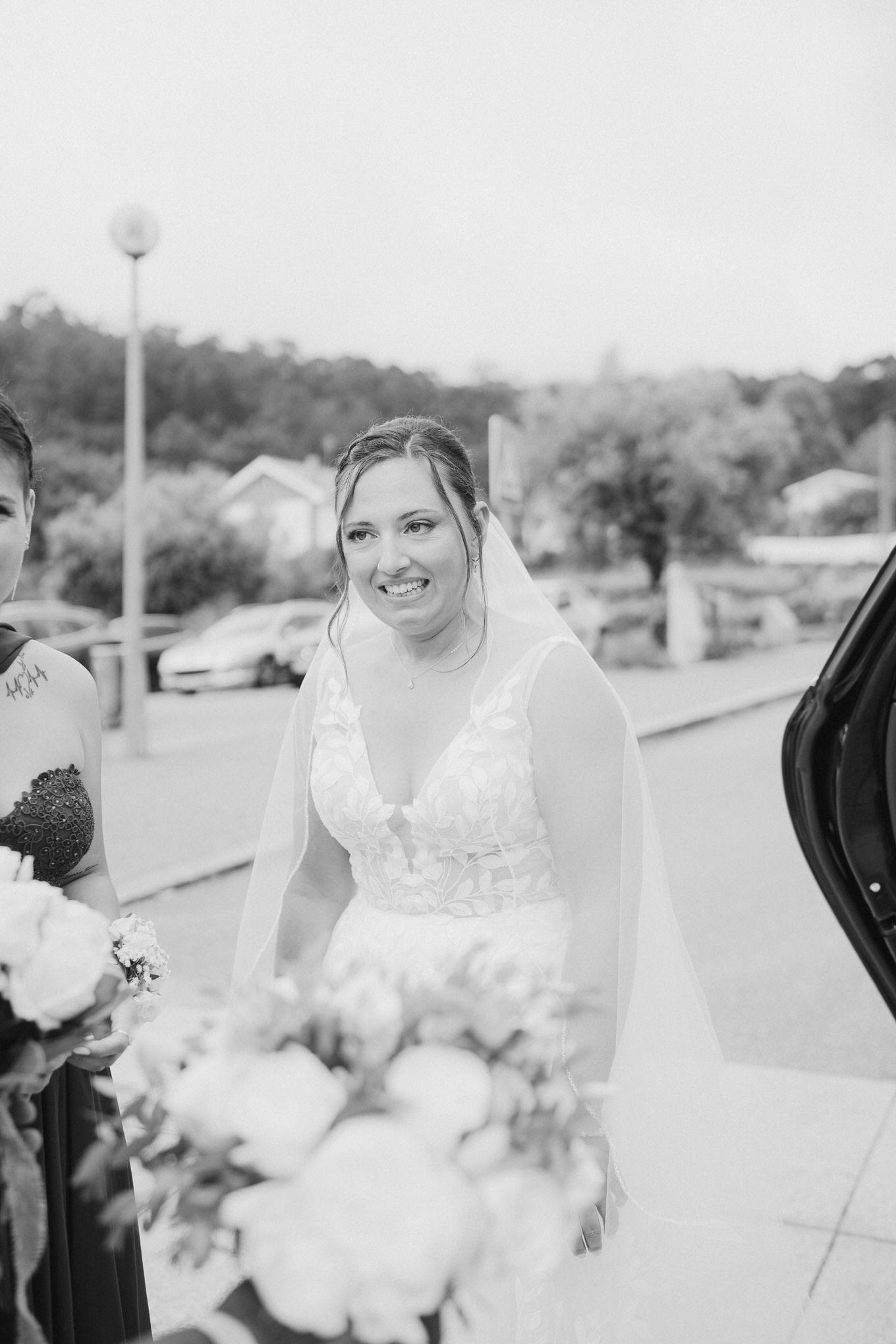 Black and white outdoor wedding photo with a person in a bridal gown holding a bouquet.