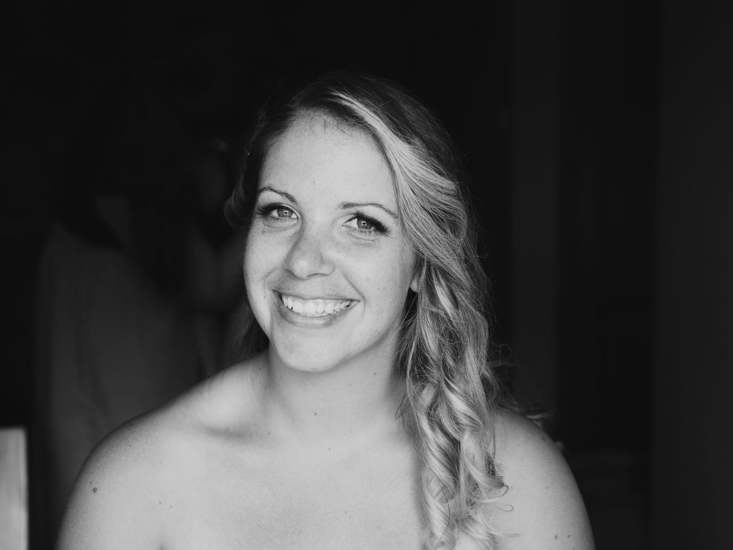 A black and white portrait shows a person with wavy hair and a warm expression looking at the camera.