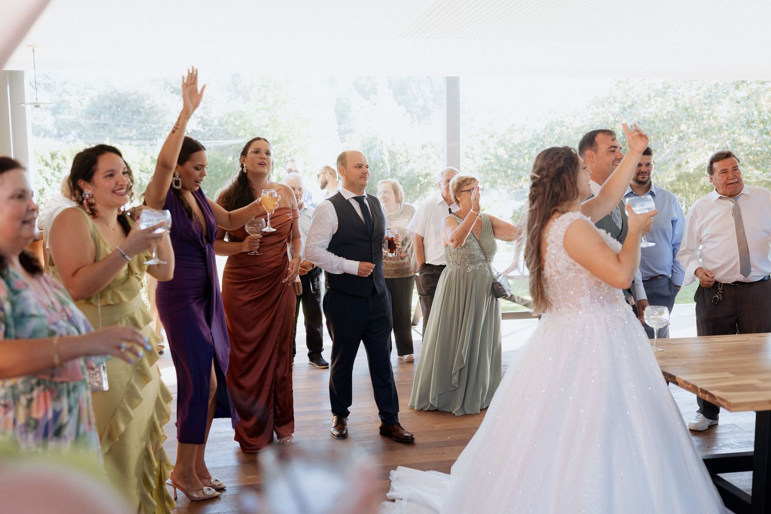Wedding guests celebrate on dance floor while couple dances nearby during joyous reception celebration indoors.