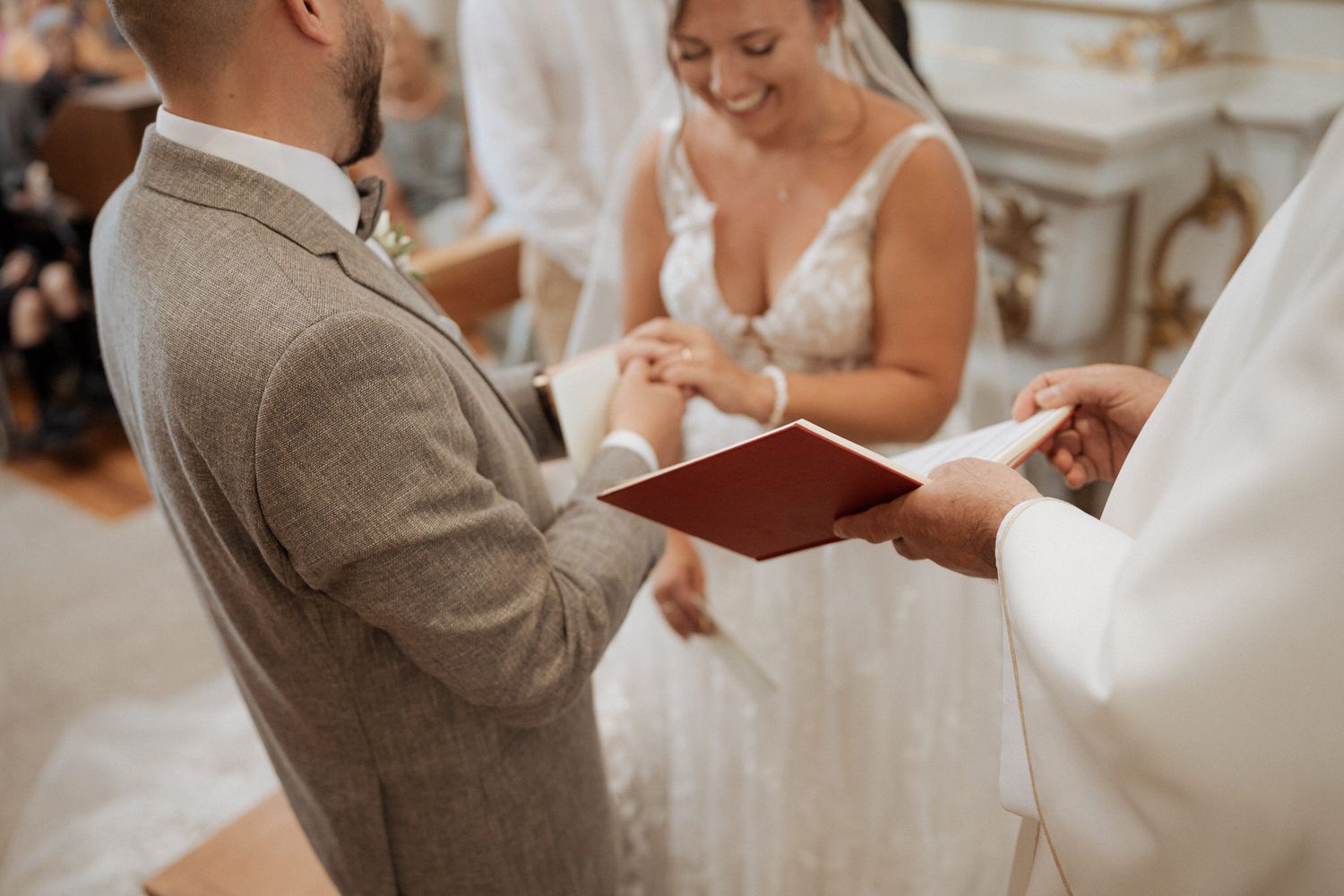A couple exchanges rings during an intimate wedding ceremony led by an officiant in formal dress.