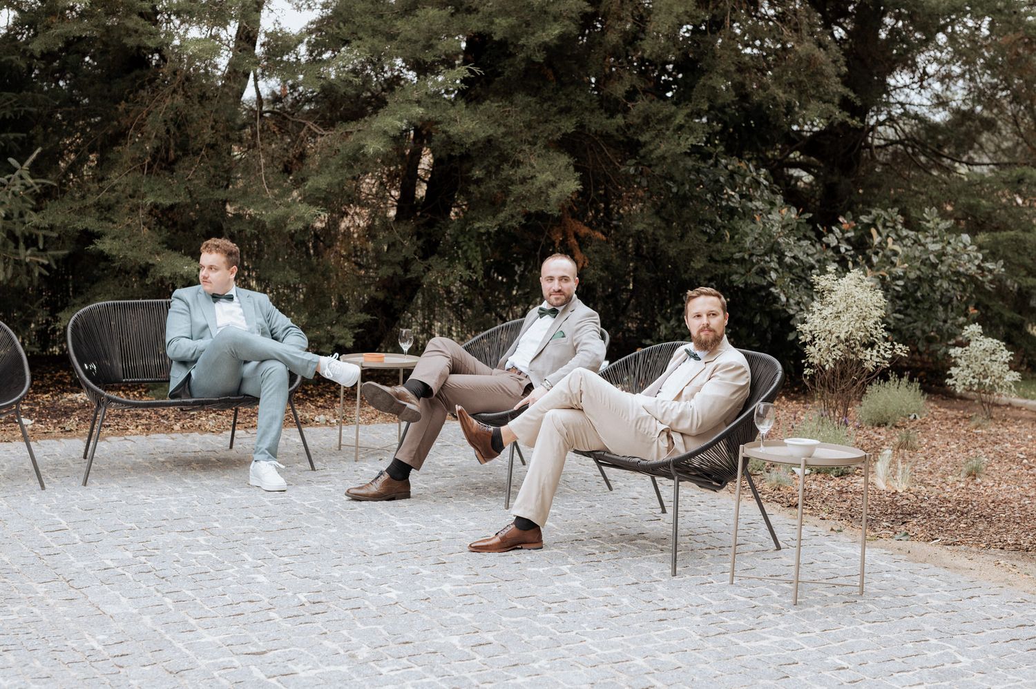 Three people relaxing in outdoor chairs having a casual conversation in a tranquil garden setting.