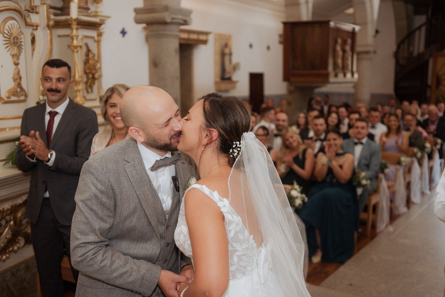A tender moment between newlyweds during their wedding ceremony in a beautiful historic church with guests watching.