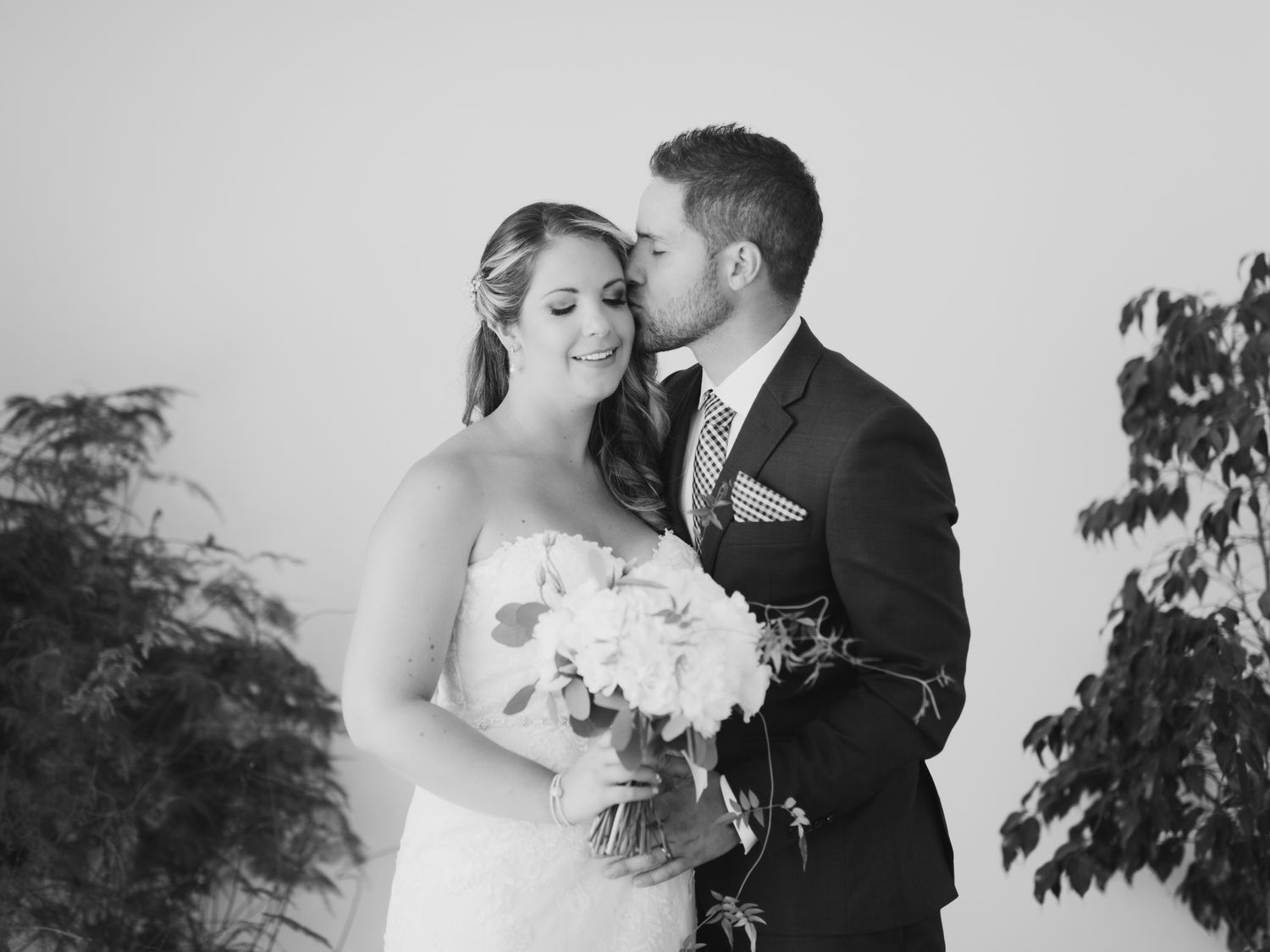Black and white romantic portrait of a couple embracing outdoors during their elegant wedding ceremony.