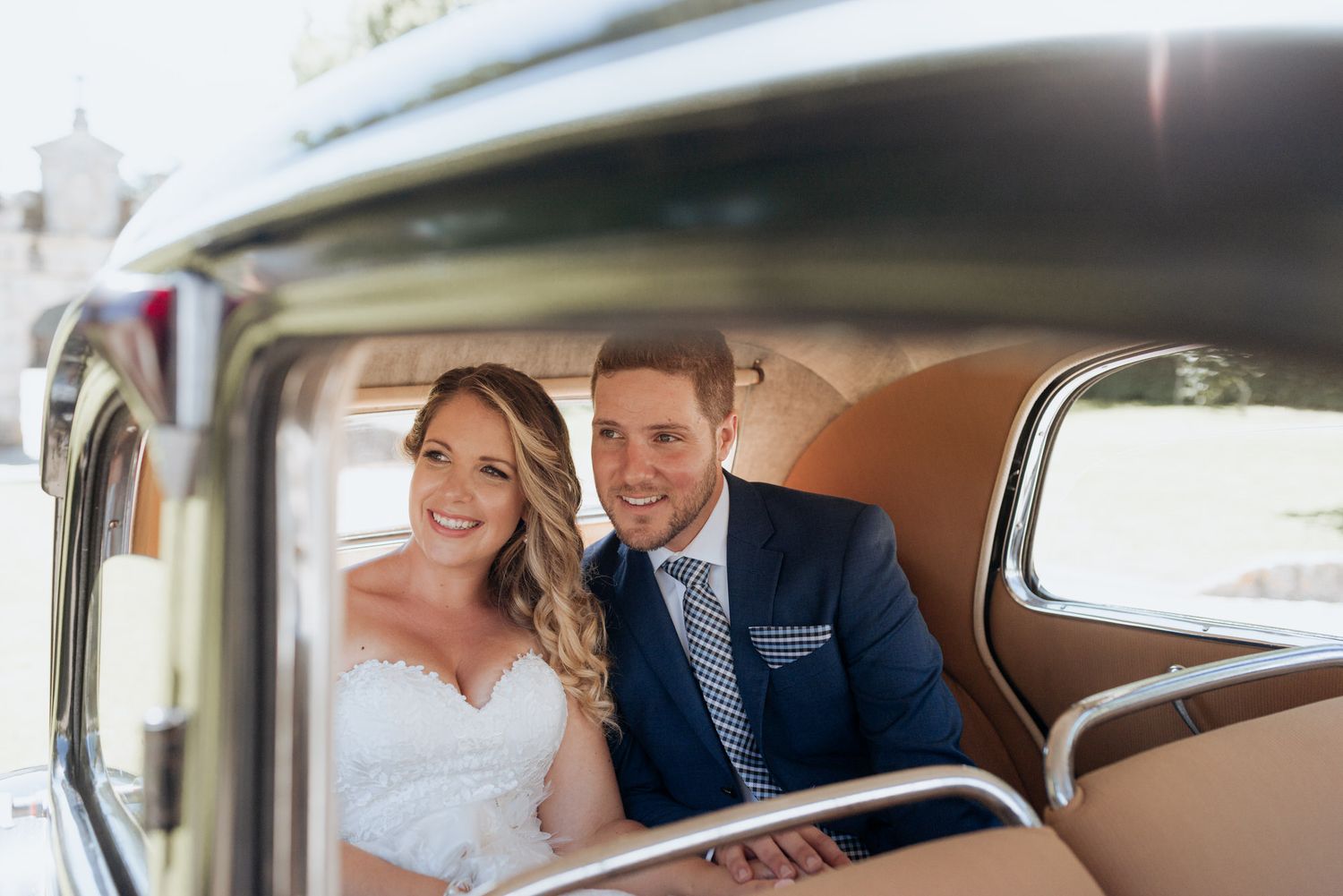 Newlywed couple shares an intimate moment together in the backseat of a classic car.