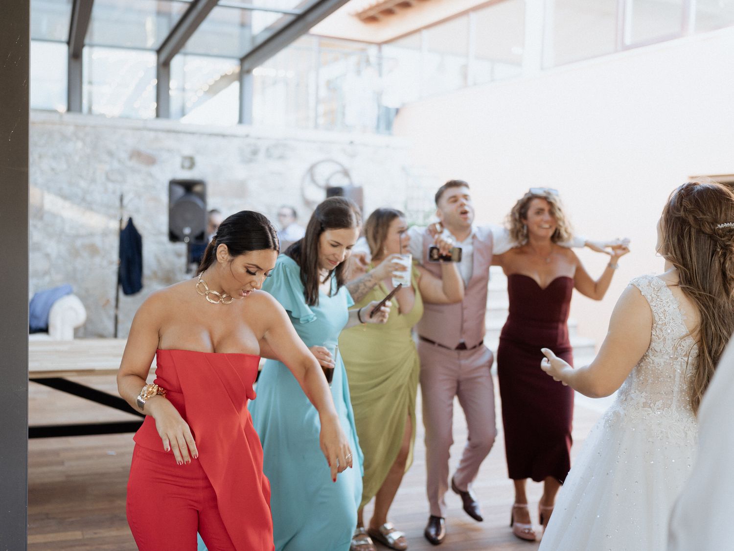 Happy wedding guests dancing together in a line during a celebration event on the dance floor.