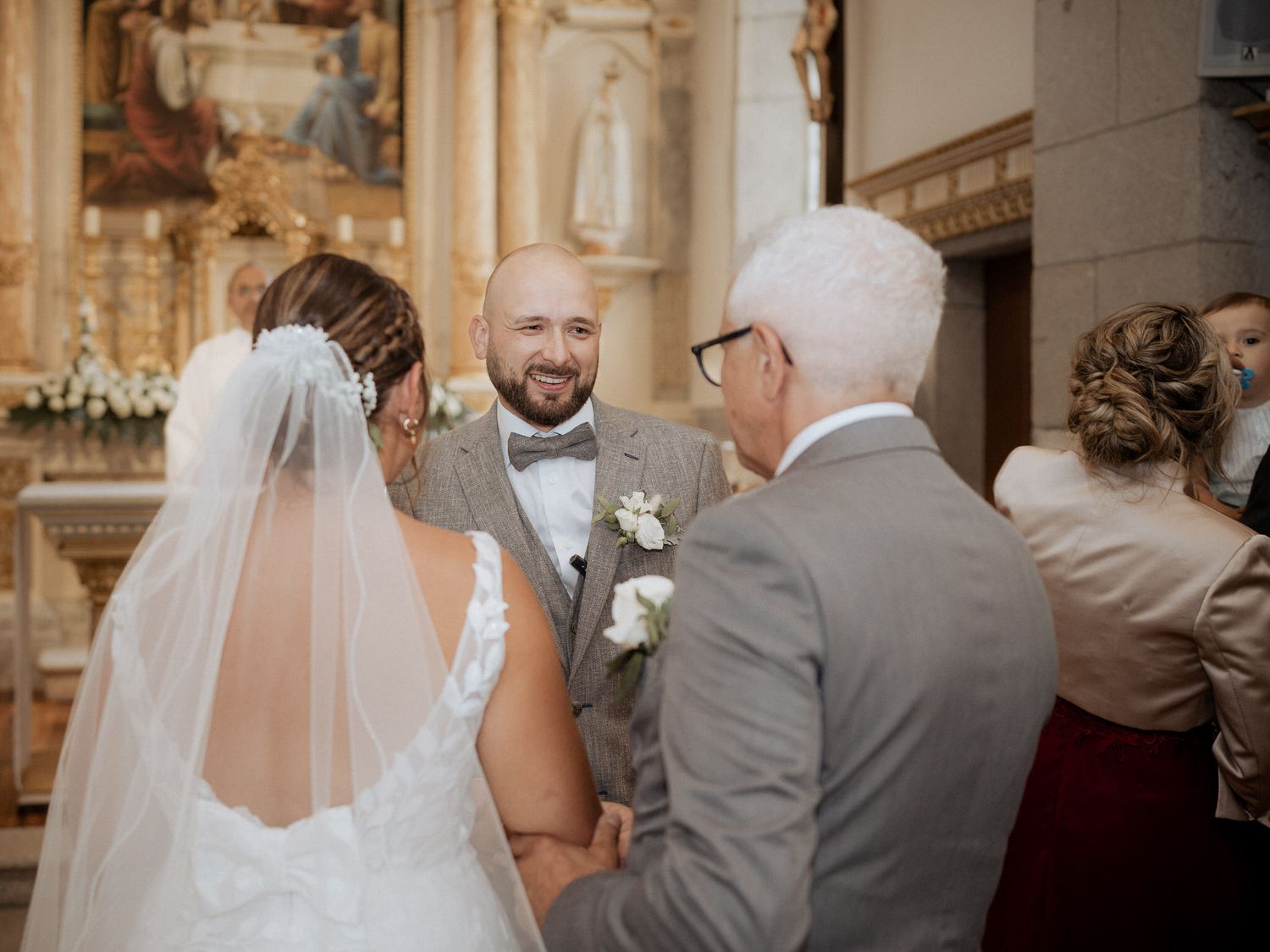 A traditional wedding ceremony takes place inside an ornate church with a couple and officiant at the altar.