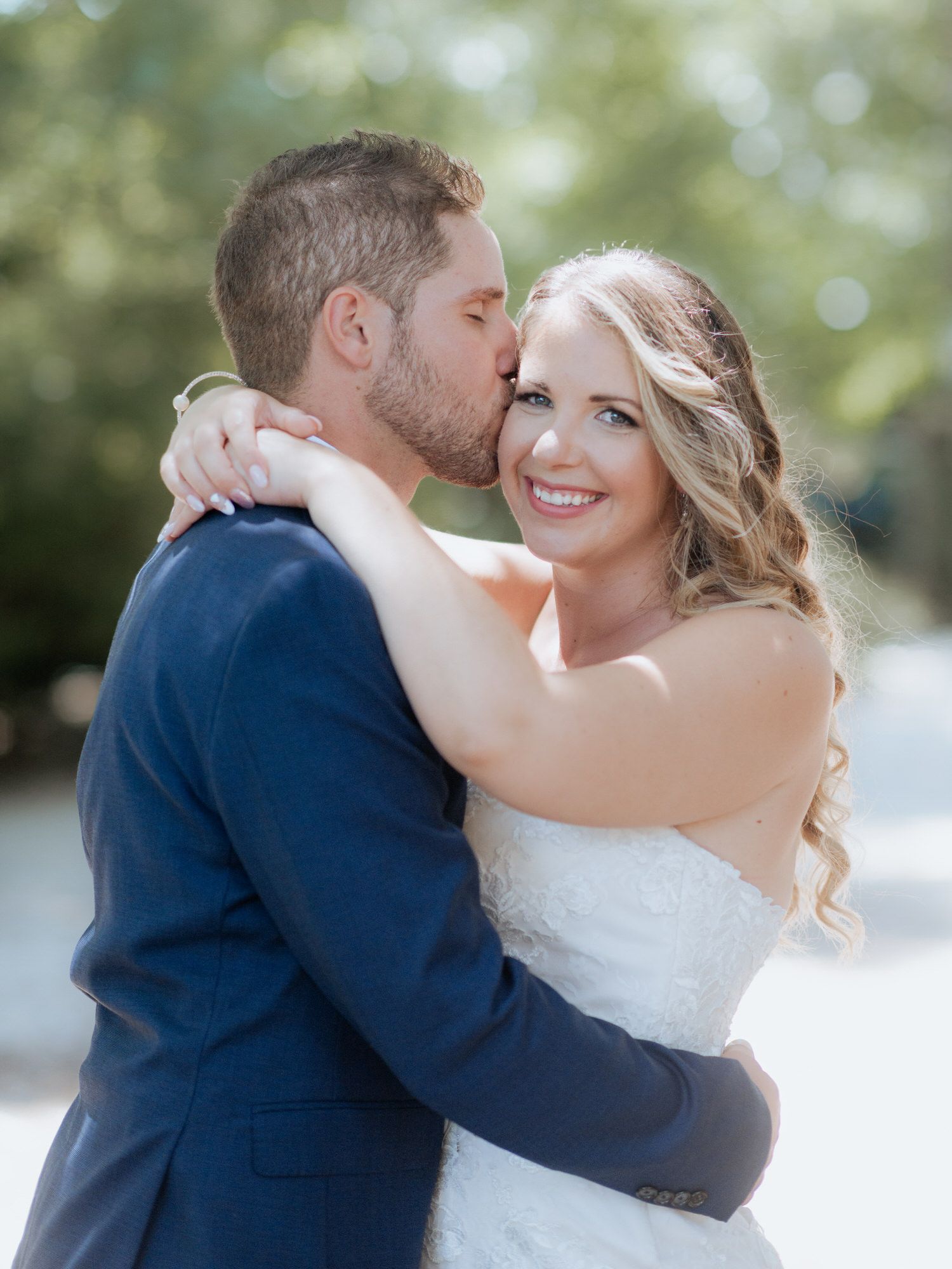 A tender moment captured between a couple on their wedding day in an outdoor setting with soft bokeh background.