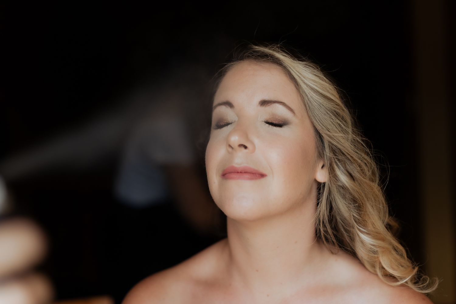 A side profile portrait in soft lighting shows a woman with blonde hair and closed eyes wearing neutral makeup.