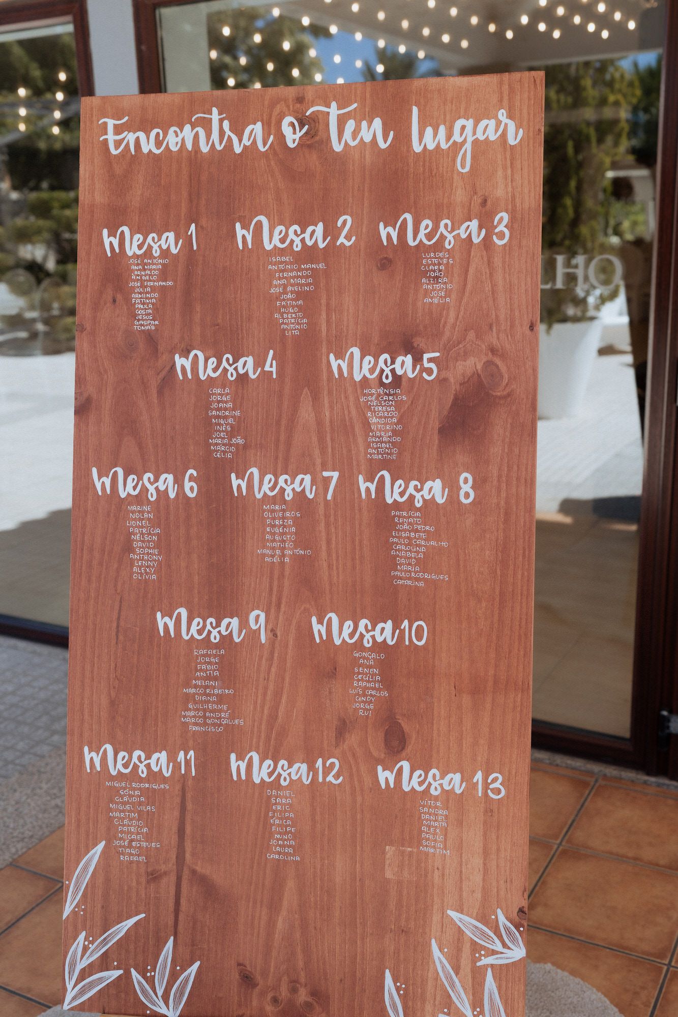 Rustic wooden seating chart display with Spanish text 'Encuentra tu lugar' and table assignments for a wedding reception.