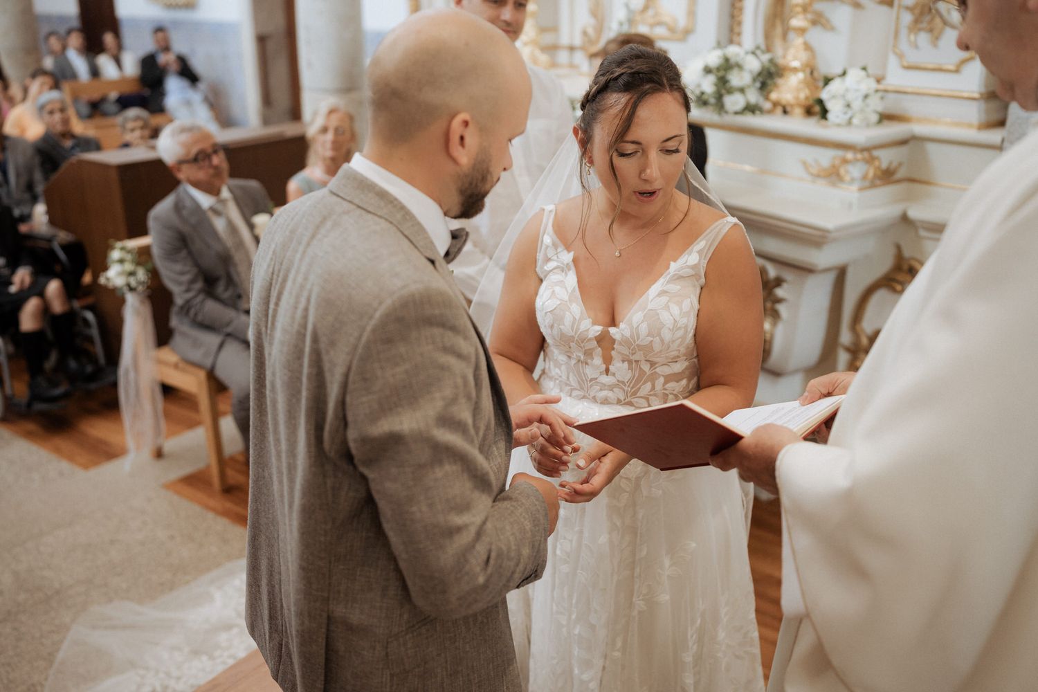 A couple exchanges wedding vows during an intimate ceremony in an elegant church setting.