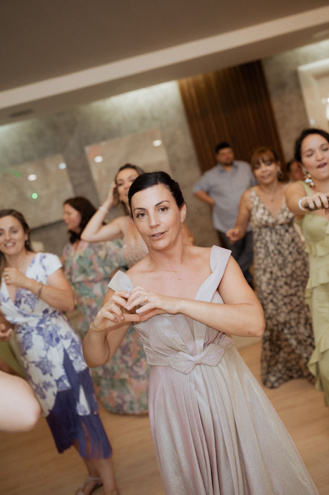 People dancing at a wedding reception in formalwear on a wooden dance floor.
