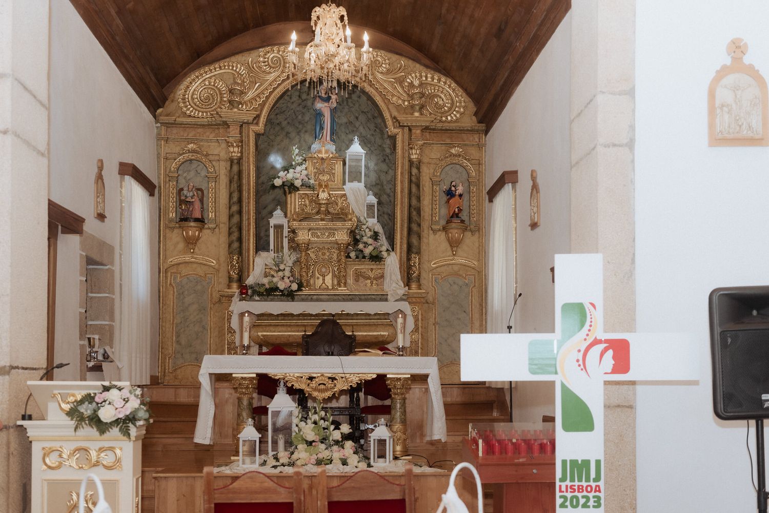Ornate gilded altar and religious decorations inside a traditional Portuguese church with vaulted wooden ceiling.