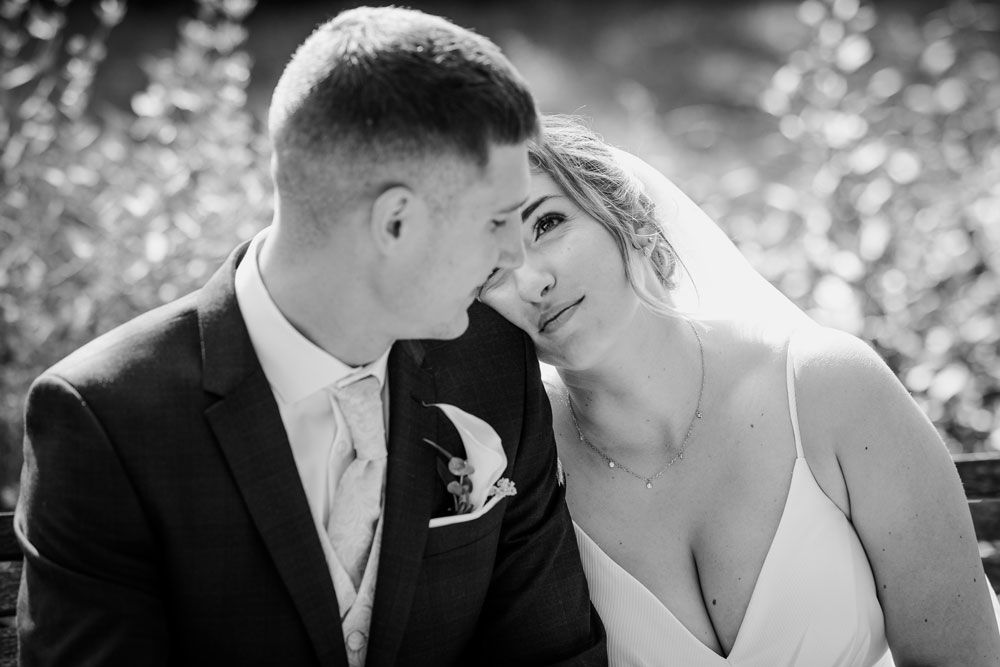 A romantic black and white wedding photo series showing tender moments between a bride and groom in a garden setting.