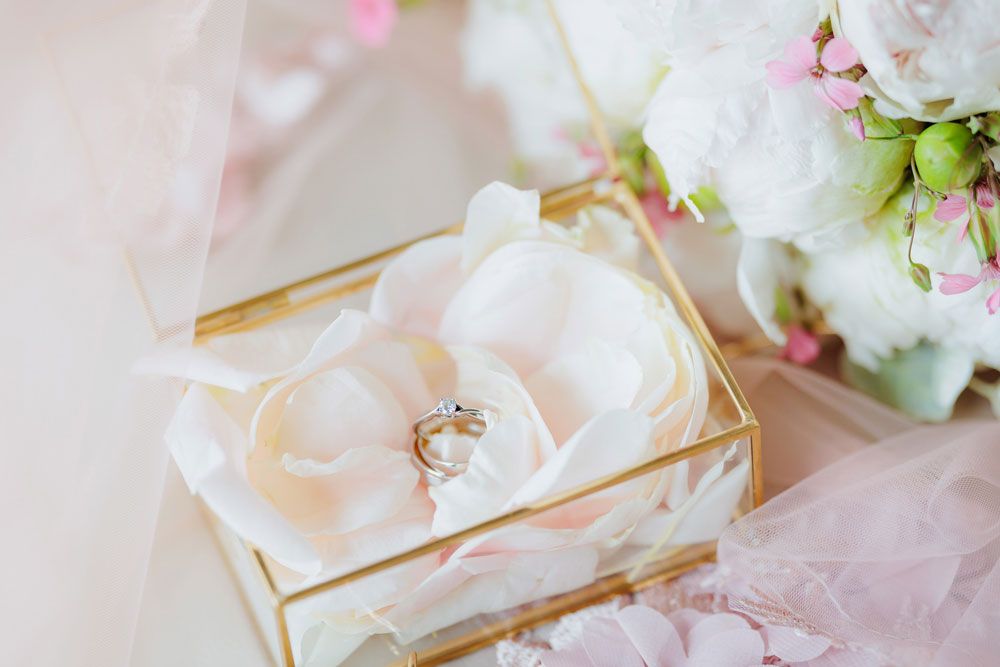 Soft pink and white roses arranged with delicate ribbons and floral accents in a romantic wedding theme.
