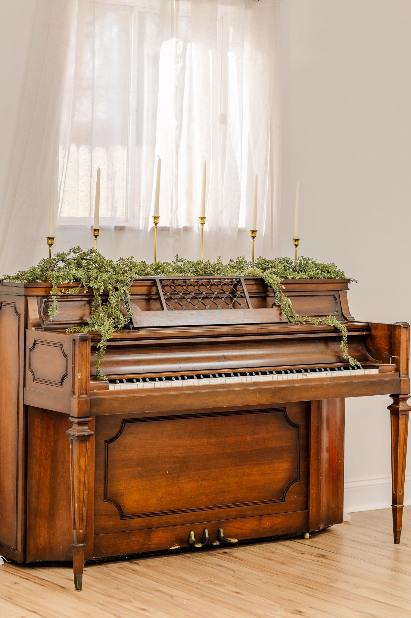 Antique upright piano repurposed as a decorative planter with green foliage growing along its wooden top surface.