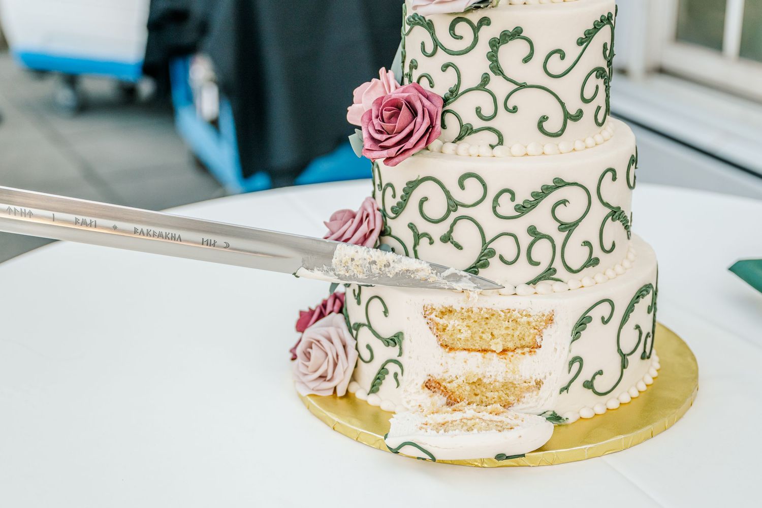 Elegant white wedding cake with green scroll details and pink sugar flowers displayed from multiple angles.