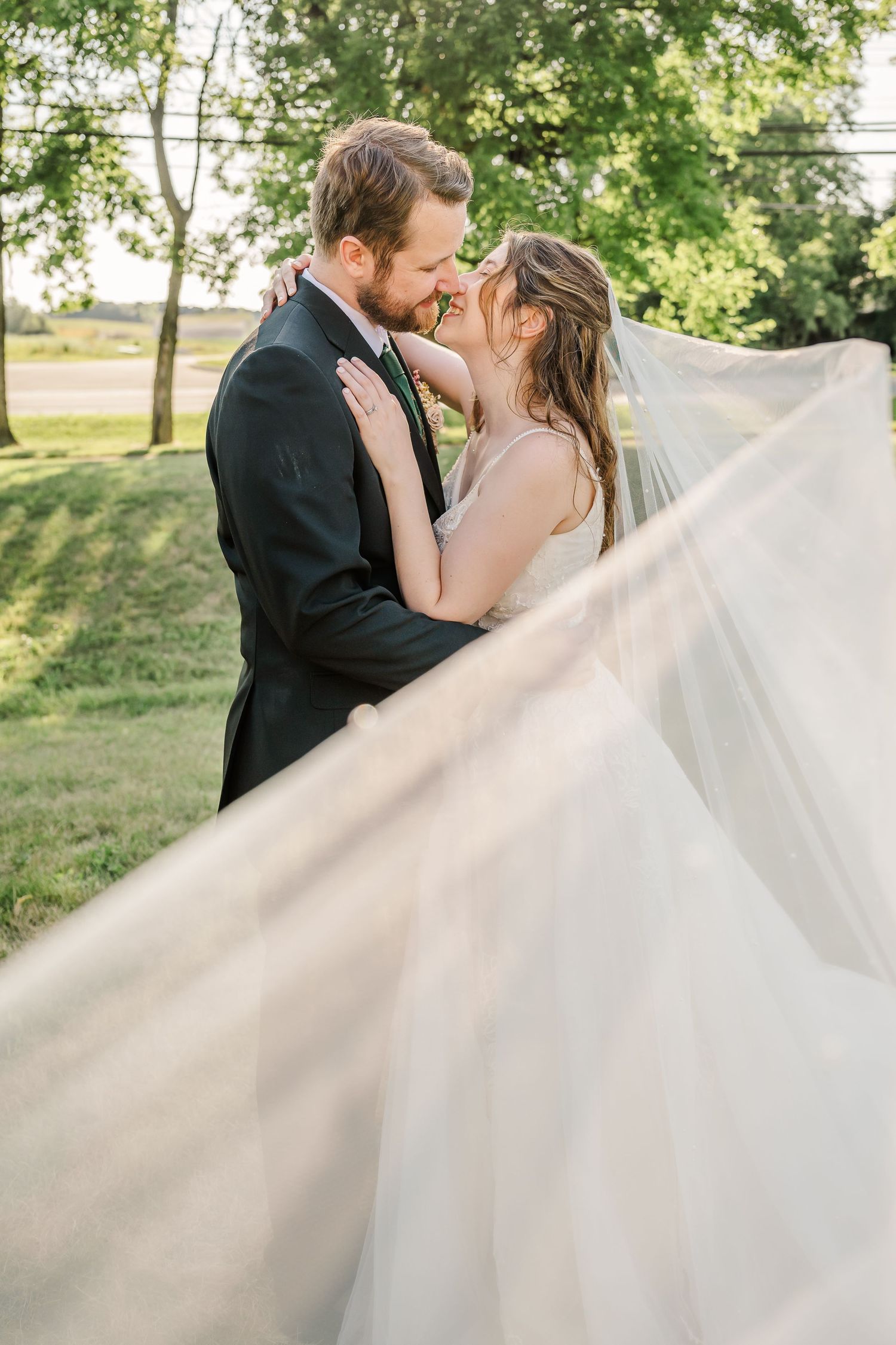 Wedding couple embracing outdoors with flowing white dress creating dramatic movement.