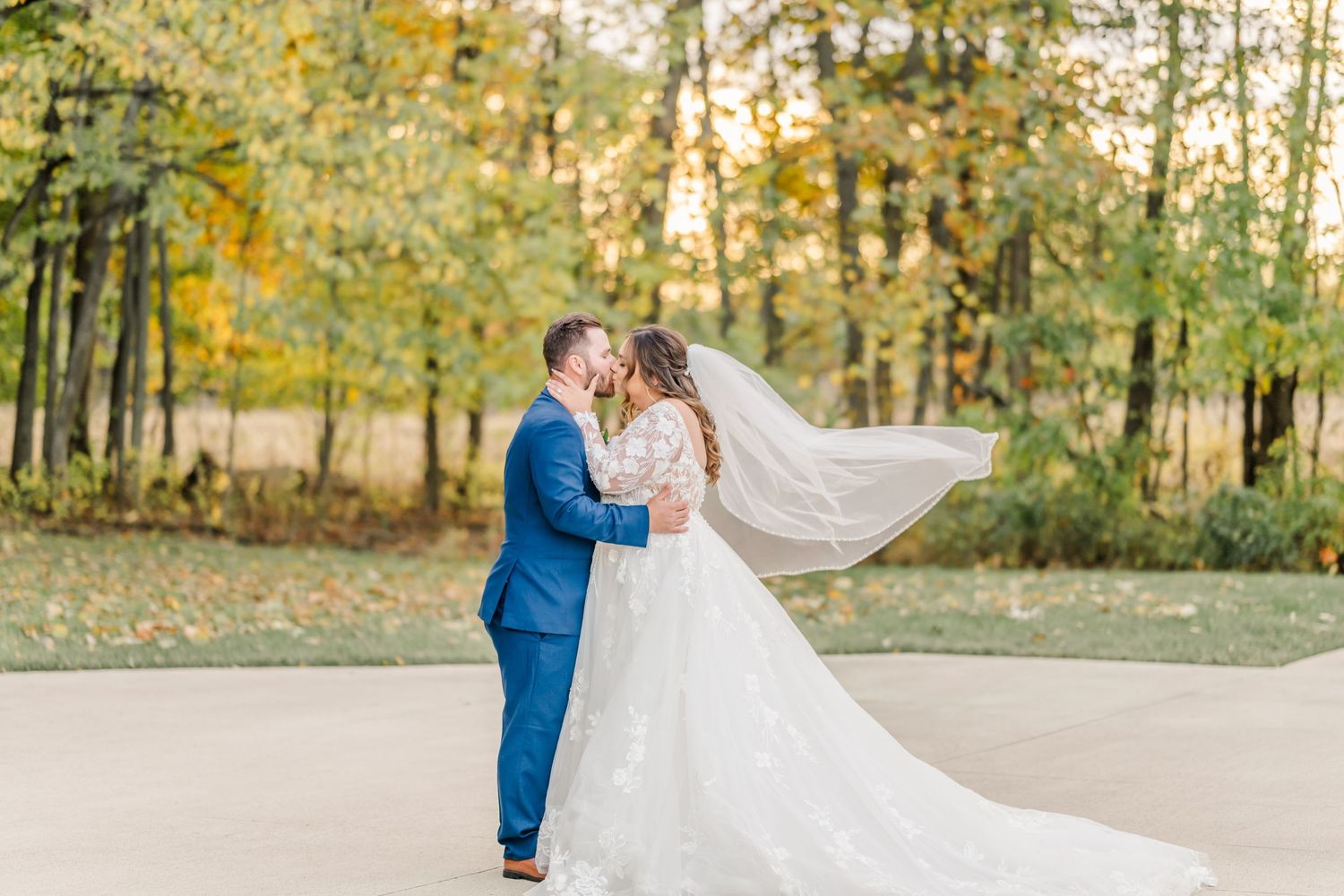 Outdoor wedding scene with couple dancing on stone patio surrounded by autumn trees. Four Seasons Barn Wedding & Event Venue
