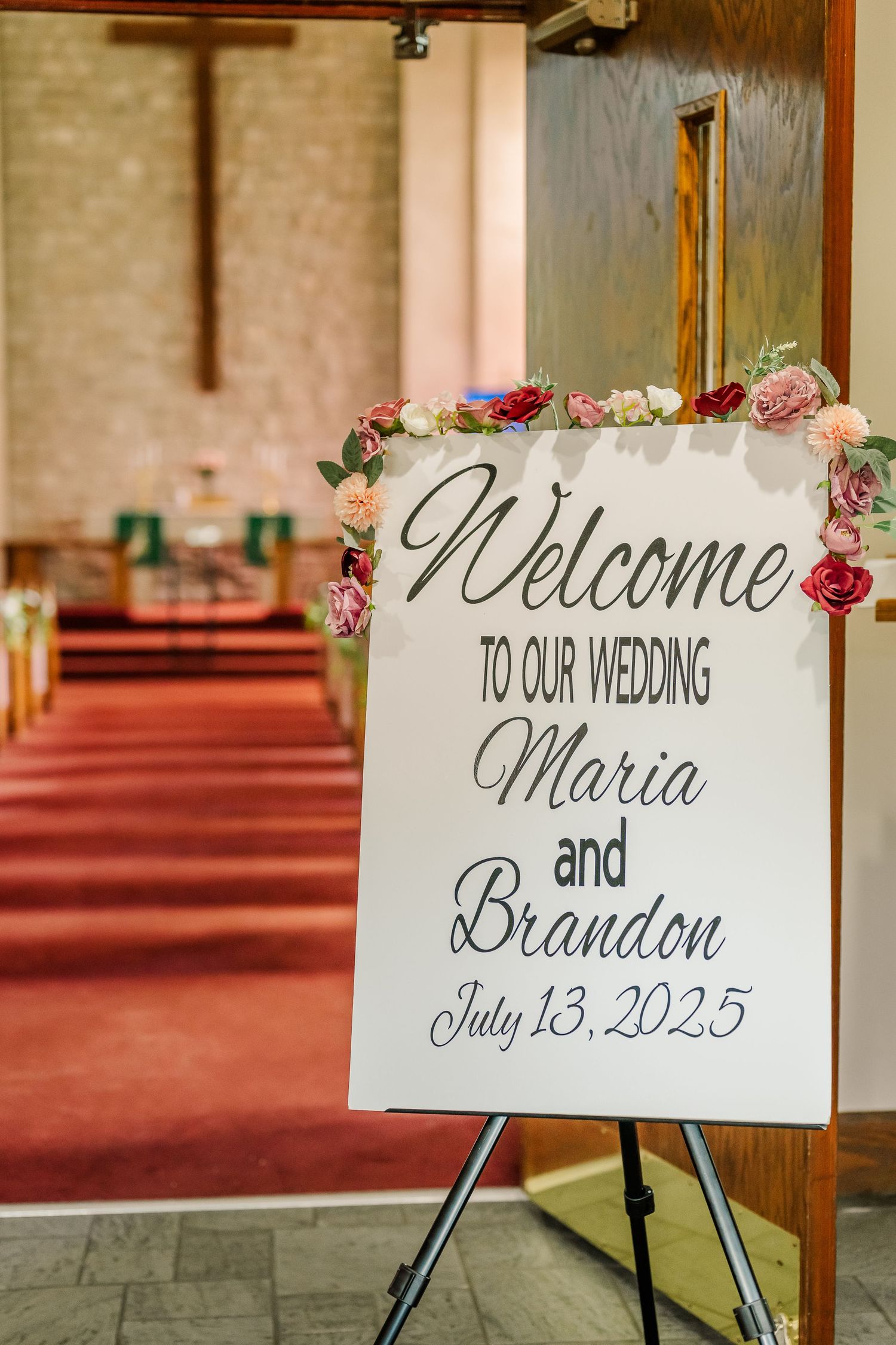 Welcome signs with elegant calligraphy and floral decorations displayed at a church wedding ceremony.