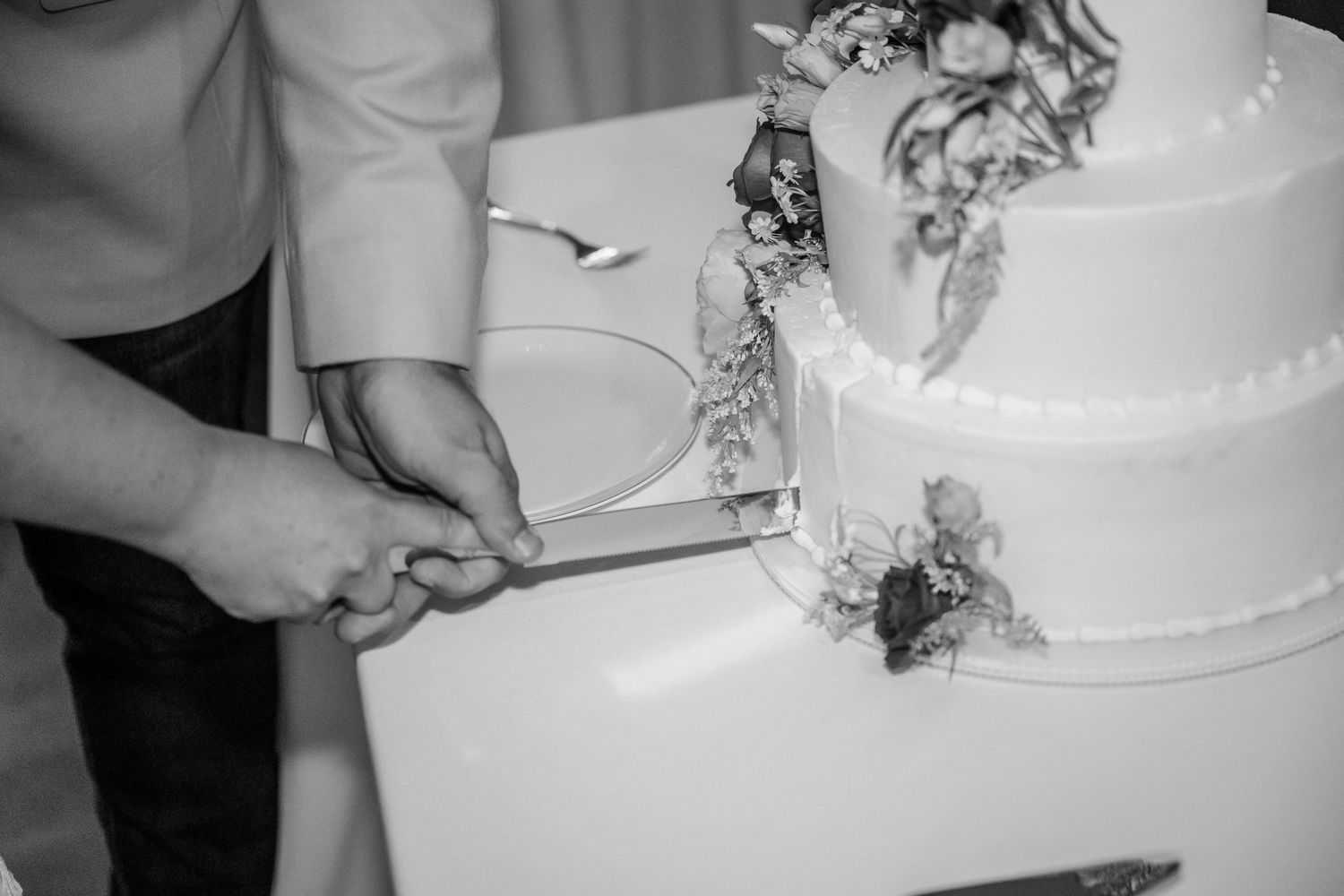 Close-up shots of a white tiered wedding cake being cut during the reception.