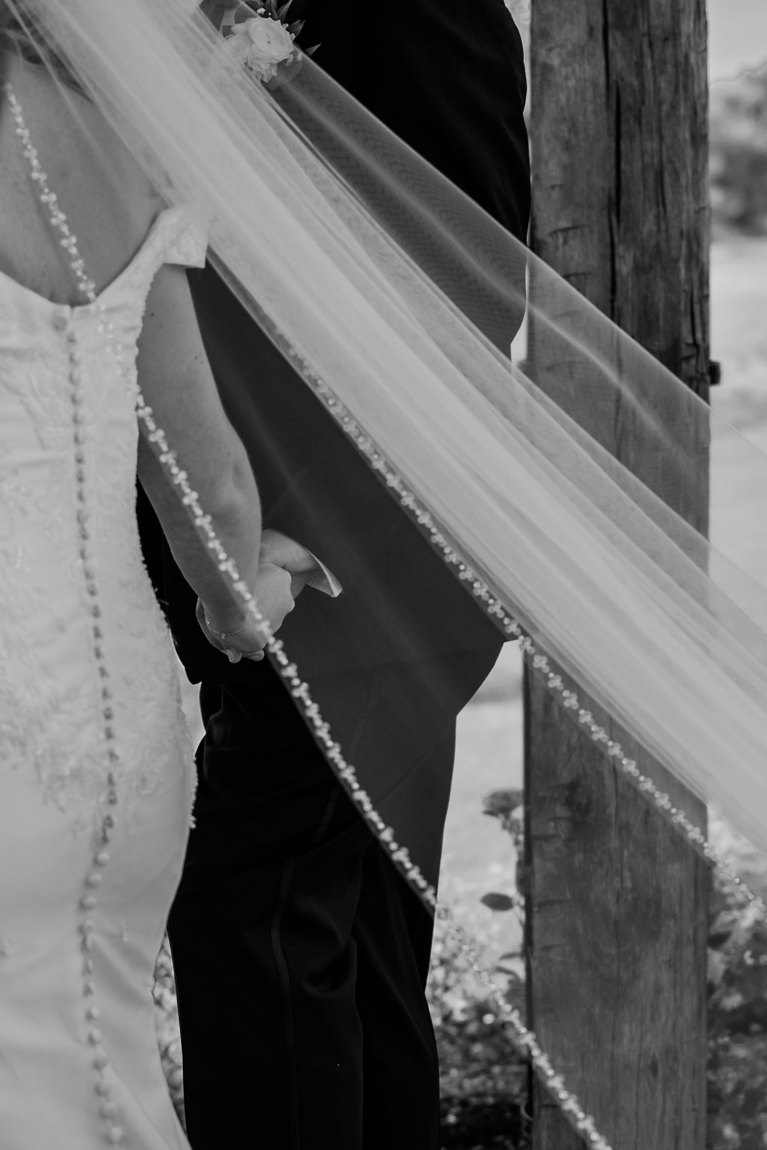 Black and white close-up detail of wedding dress buttons and lace trim against dark fabric.