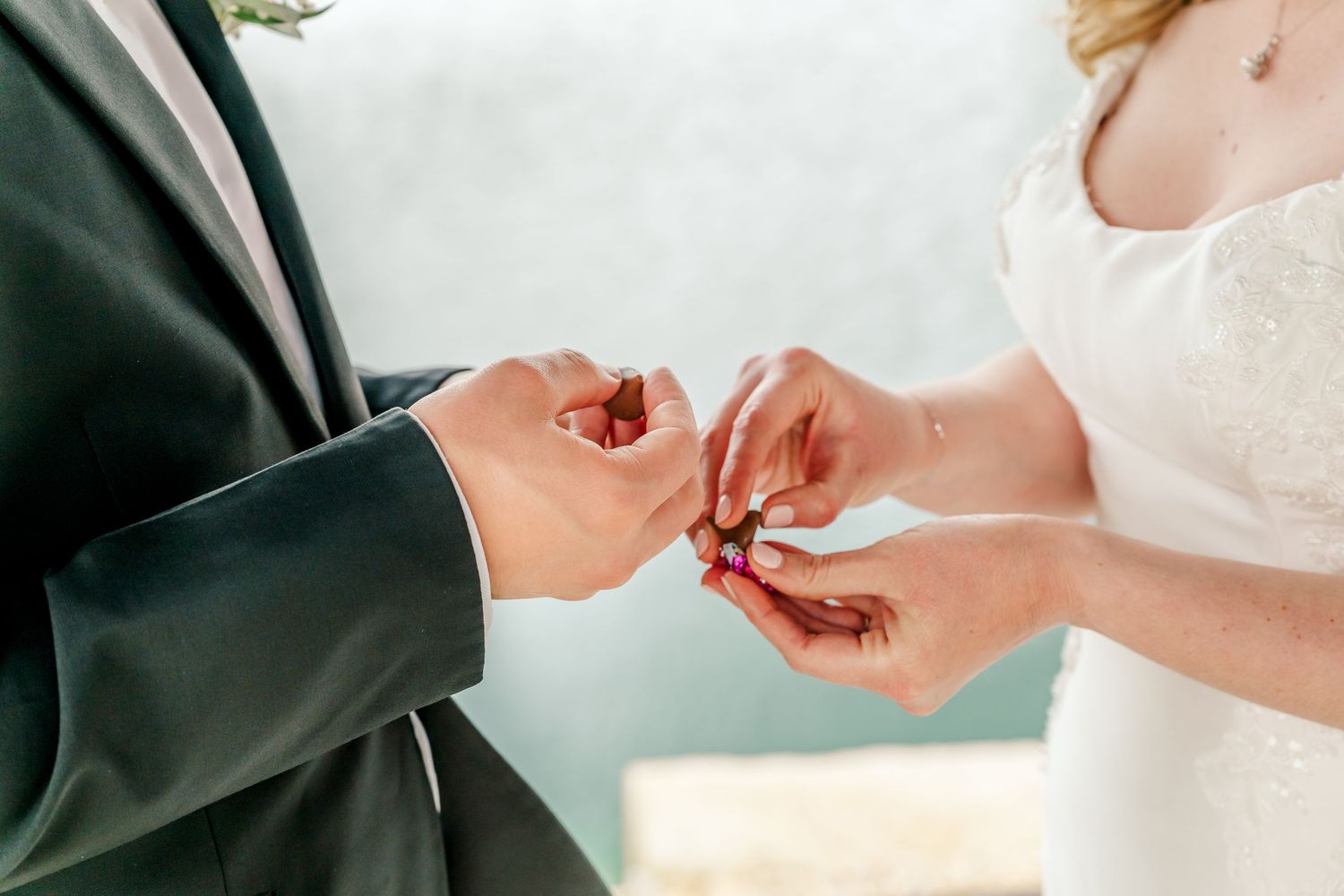 Close-up shots of hands exchanging wedding rings during an intimate ceremony in natural lighting.
