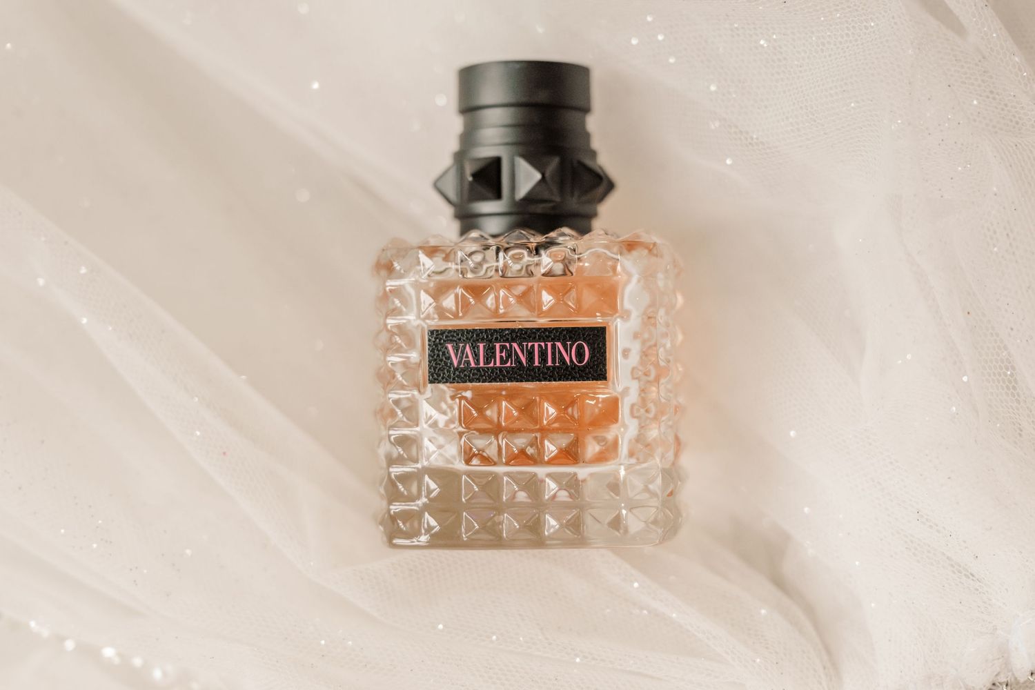 Luxury perfume bottle with studded glass design photographed from multiple angles on white background.