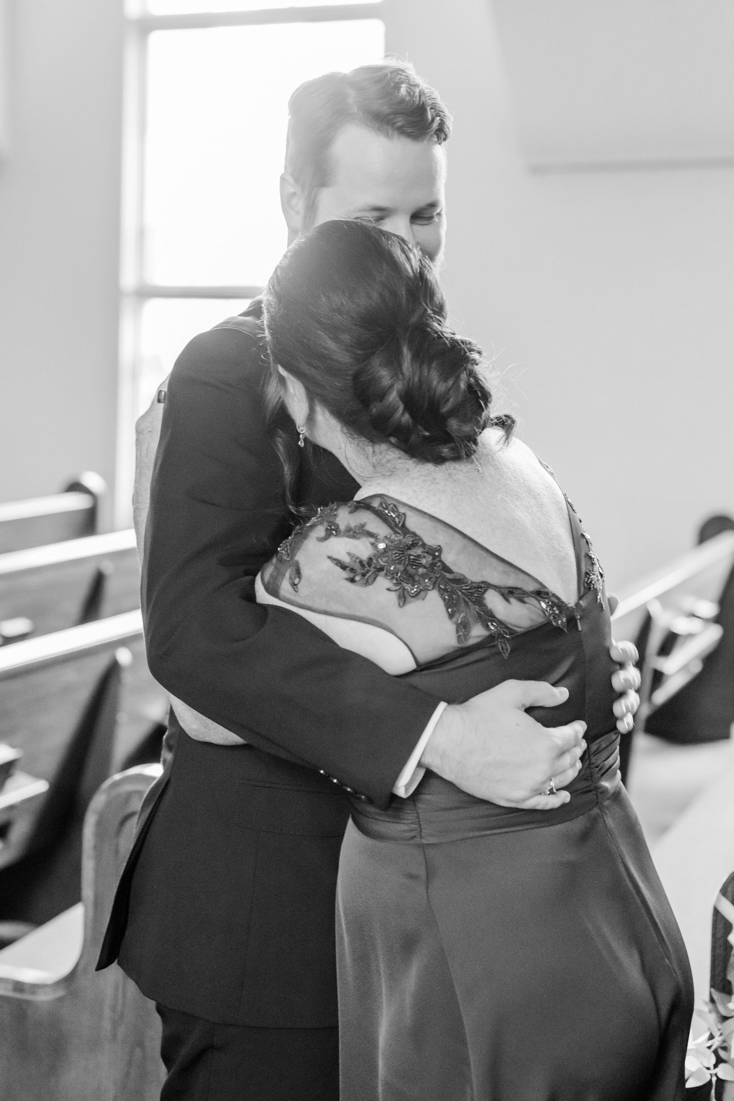 Intimate embrace between wedding attendees during an emotional church ceremony moment.