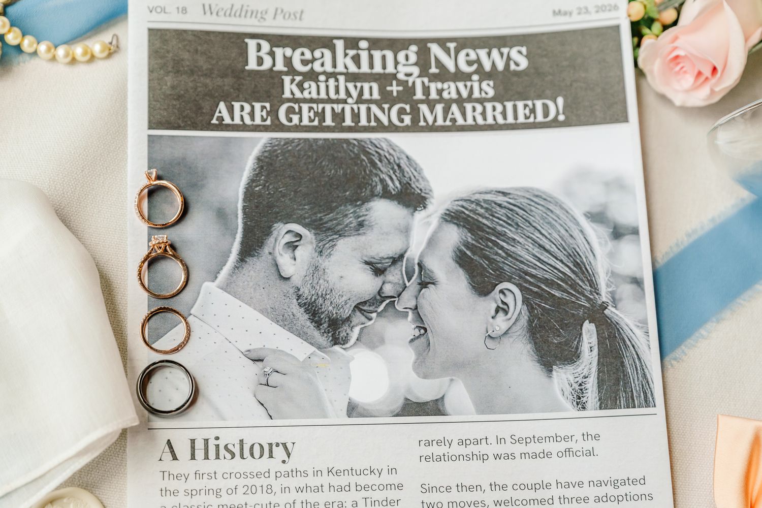 Wedding announcement newspaper with rings and floral decor on a flat lay display. The Old Barns at Dry Run Farms in Williamsport, Ohio.
