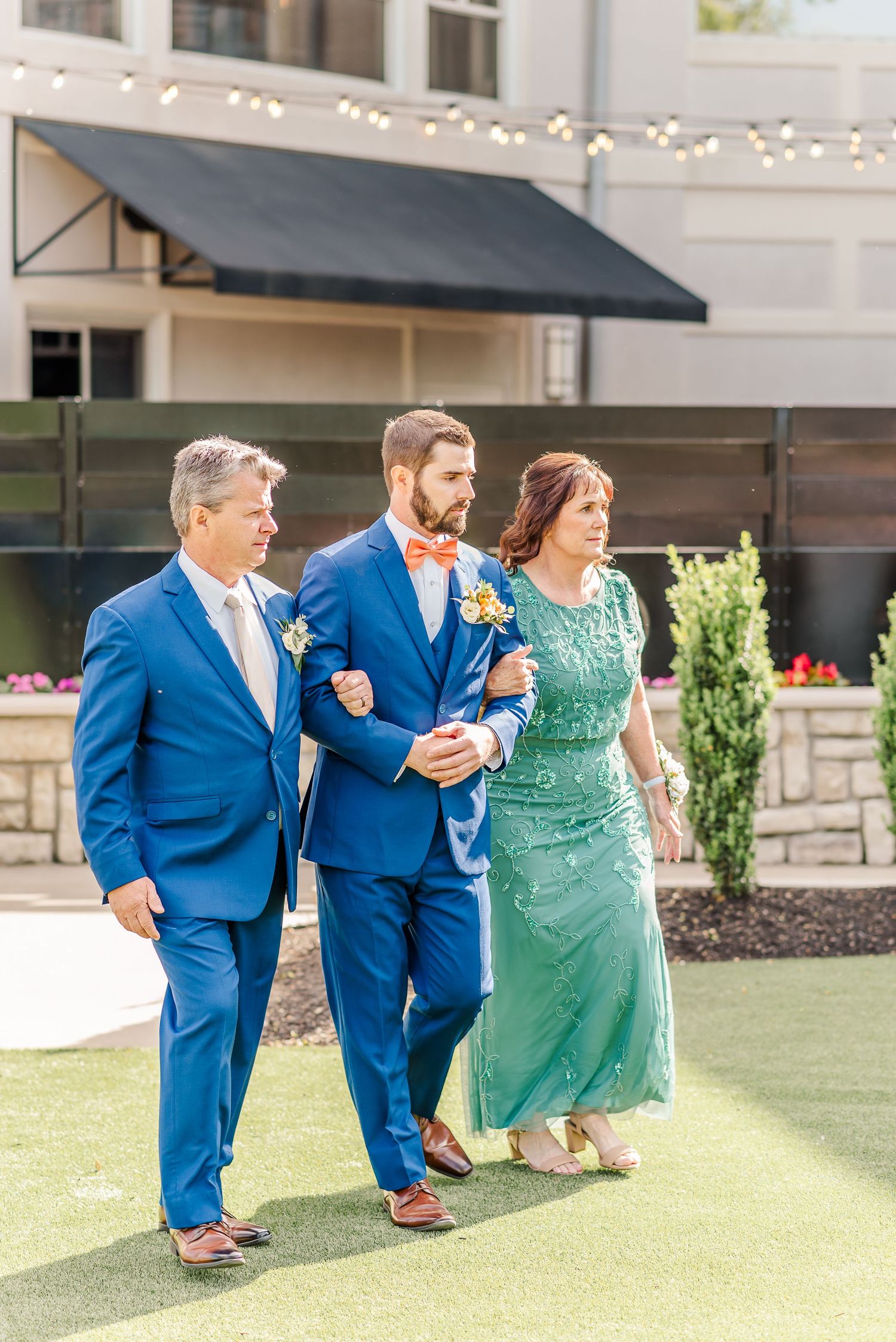 Wedding party in bright blue suits and emerald green dress pose playfully in sequence of outdoor photos.
