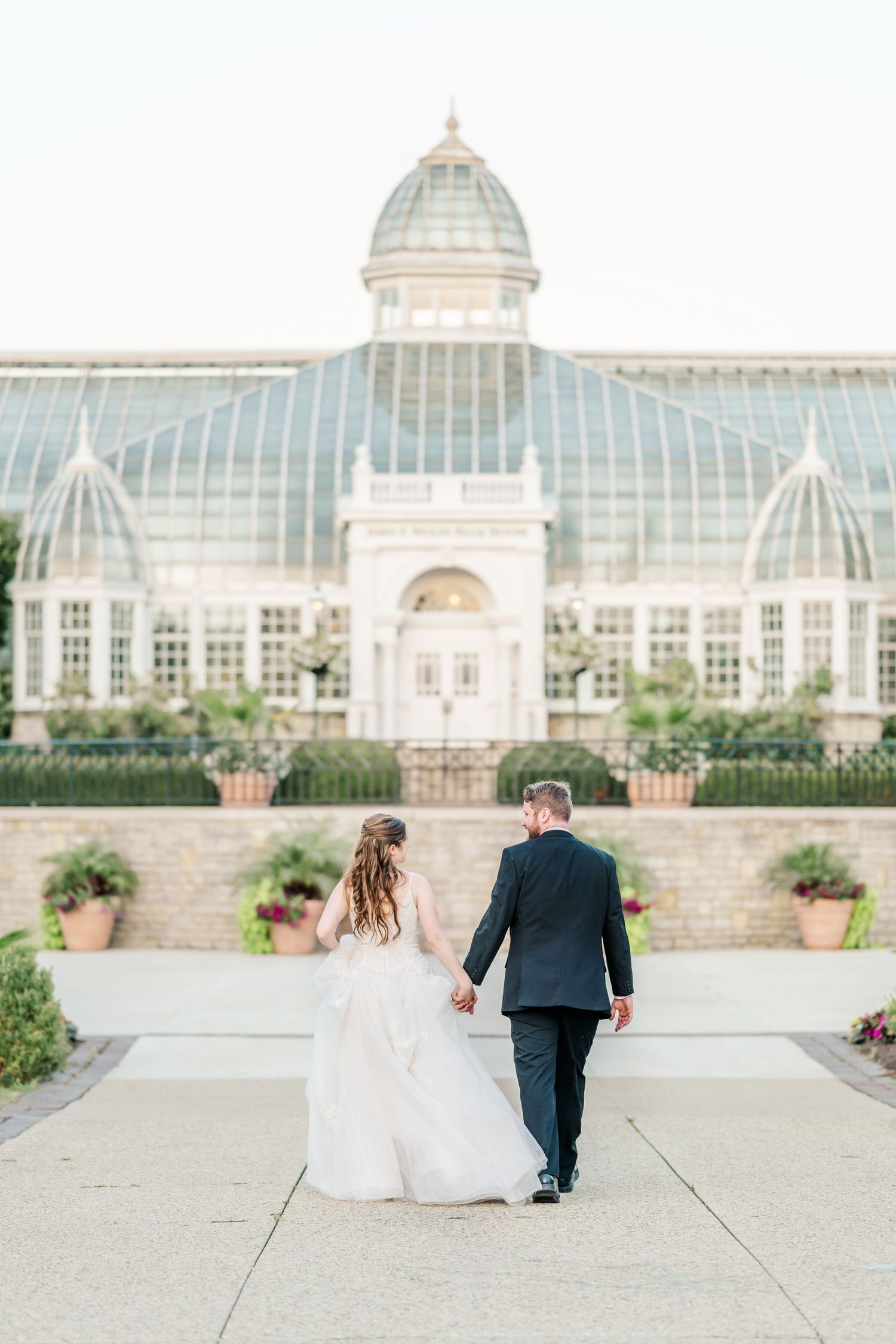 Elegant conservatory building with white architectural details and glass dome on a sunny day.