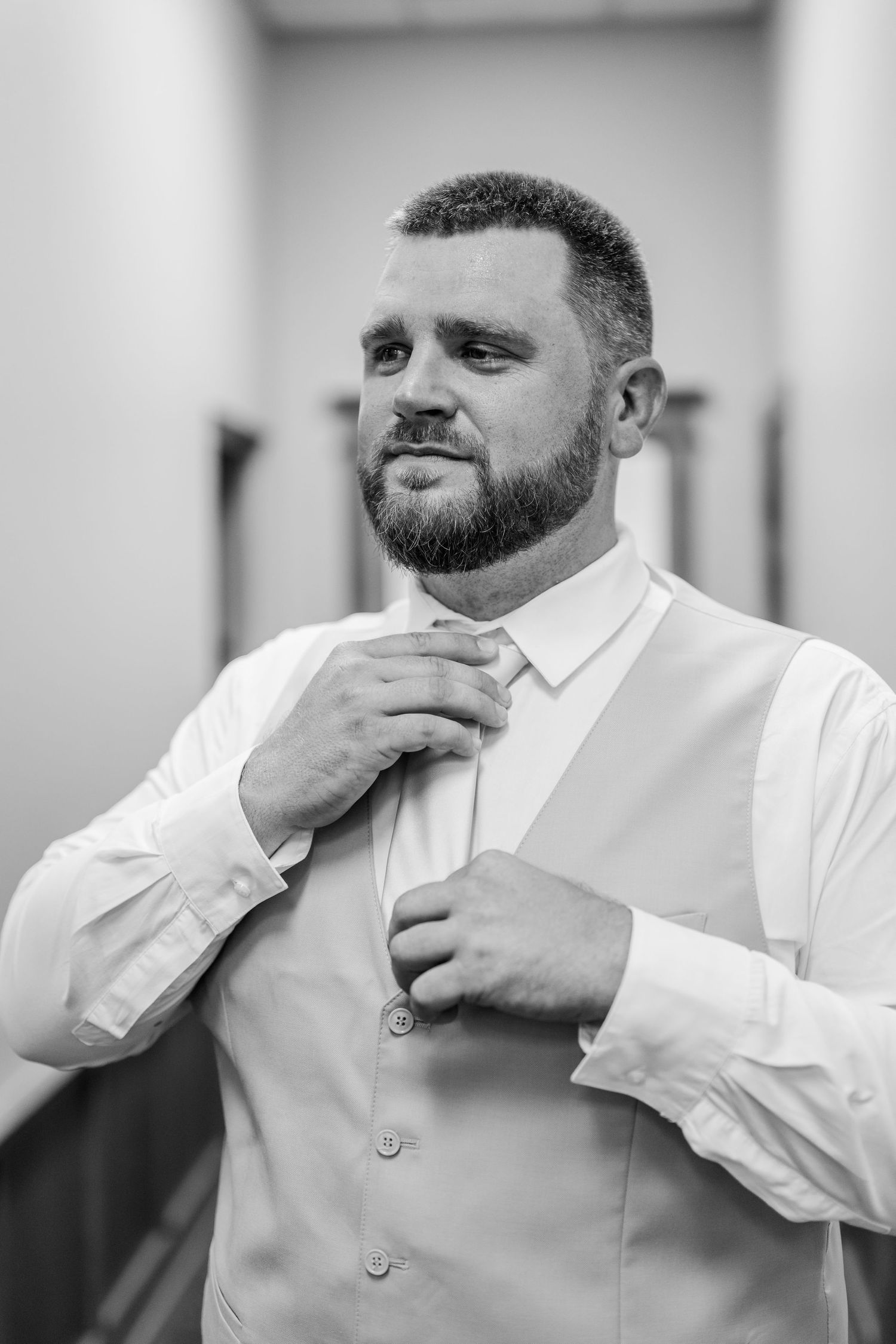 A series of black and white photos showing a bearded man in a white dress shirt adjusting his collar and beard.